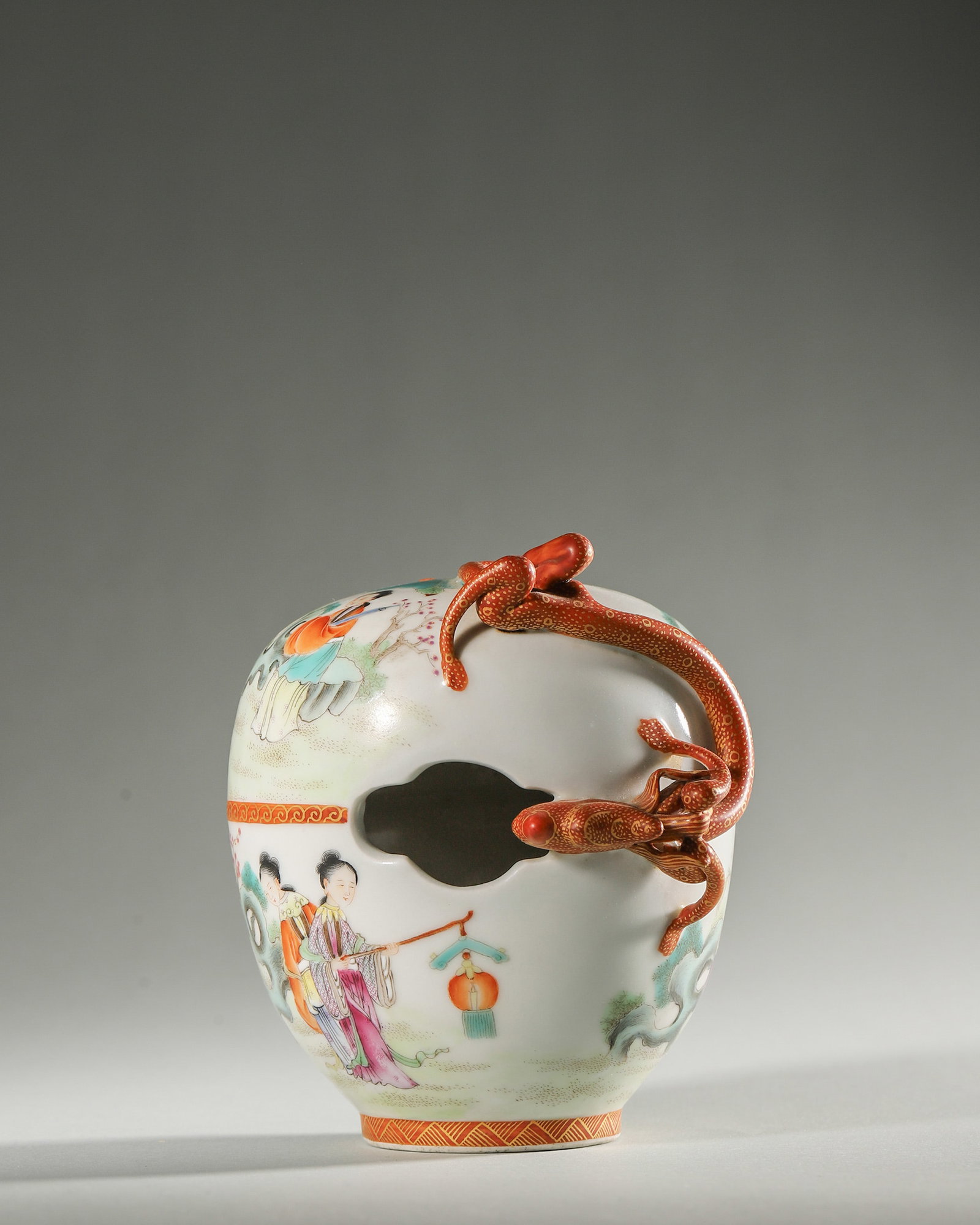 A FAMILLE-ROSE OPENWORK JAR WITH LADIES AND APPLIED CHILONG: A rounded famille-rose porcelain jar painted with ladies in a garden, with an applied iron-red and gilt chilong to the shoulder and begonia-form openwork. Diam. 9 cm; Ht. 10 cm.