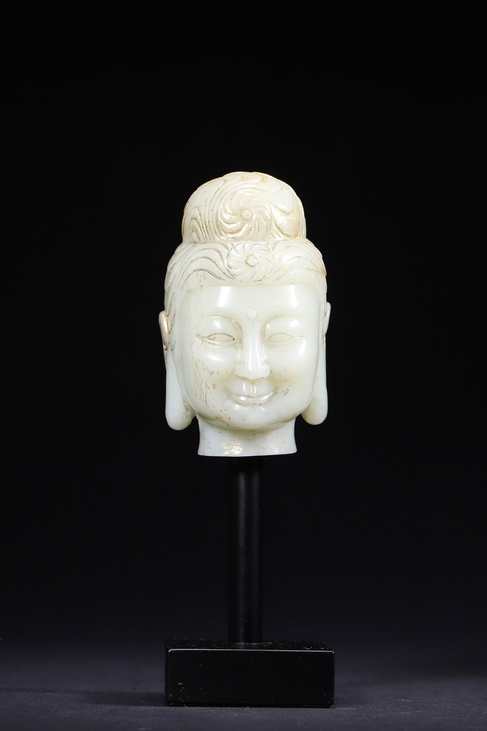 A GILT-DECORATED WHITE JADE BUDDHA HEAD: A white jade Buddha head carved with serene facial features and gilt details to the hair. L. 5.1 cm; W. 5.5 cm; Ht. 8.5 cm; Wt. 343 g.