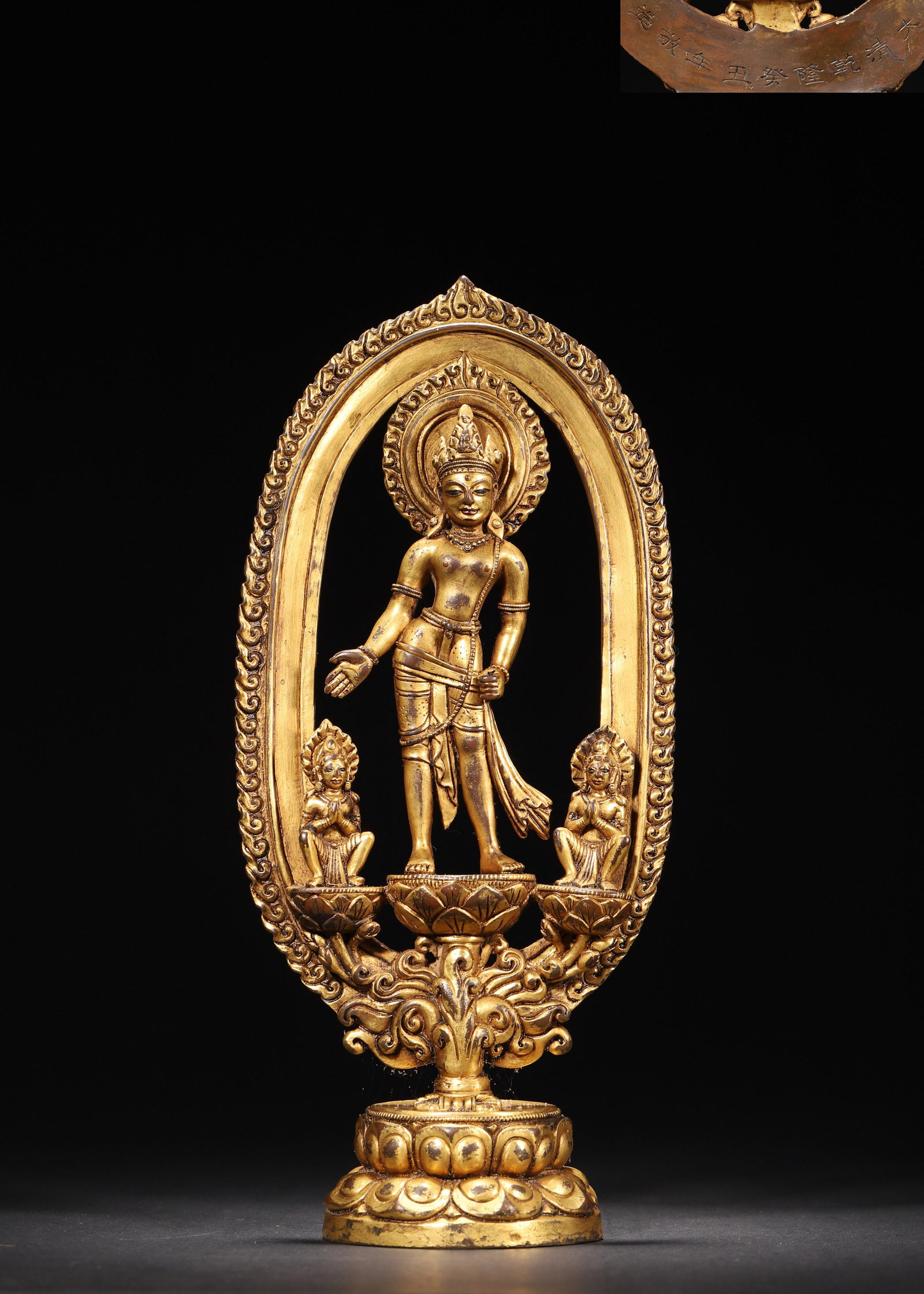 A GILT-BRONZE STANDING FIGURE OF AVALOKITESVARA: A gilt-bronze standing figure of Avalokitesvara with an openwork aureole and two attendant figures. L. 12 cm; W. 7 cm; Ht. 26 cm; Wt. 1,073 g.