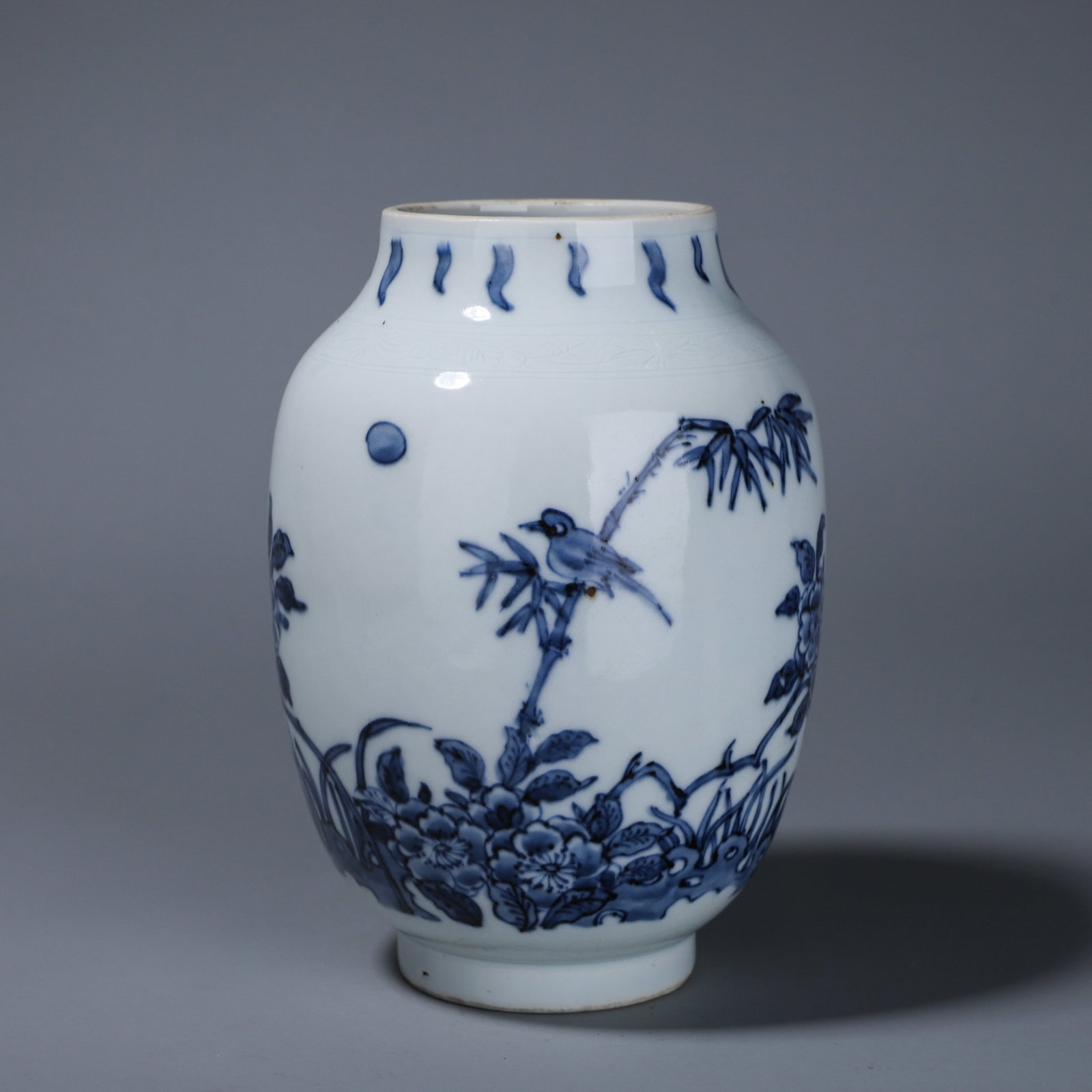 A BLUE-AND-WHITE 'BIRD, BAMBOO AND FLOWERS' LOTUS-SEED JAR: A blue-and-white porcelain lotus-seed jar painted with bamboo, a bird, peonies and a butterfly, with subtle incised scroll decoration to the body. W. 11 cm; Ht. 17 cm.