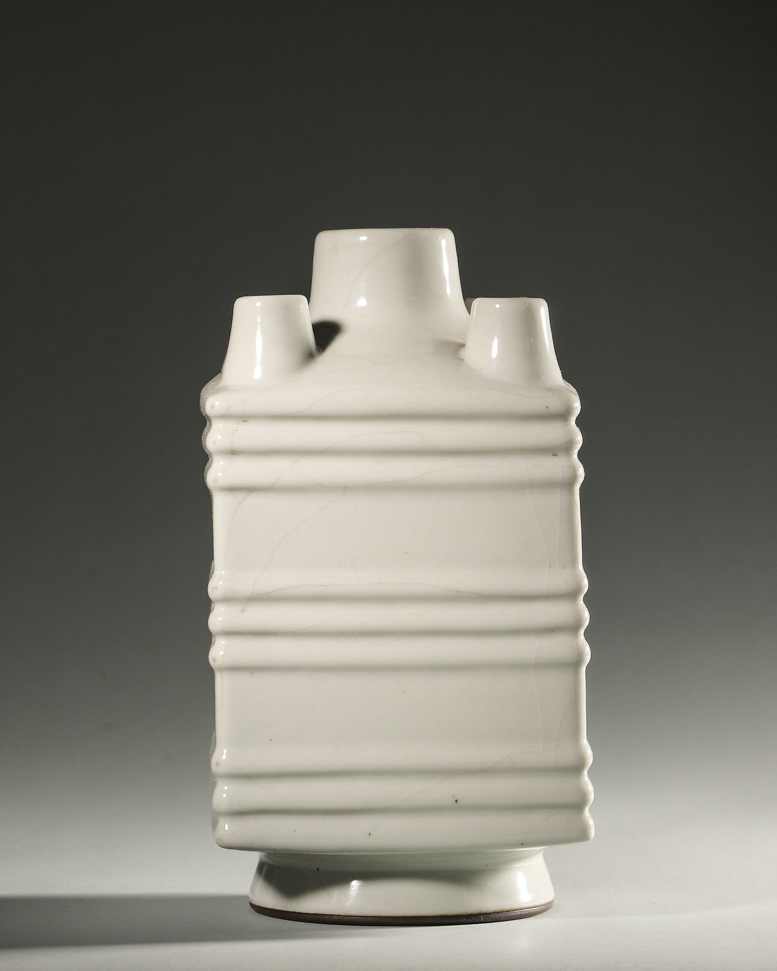 A WHITE-GLAZED FIVE-MOUTHED PORCELAIN VASE: A white-glazed porcelain vase with five mouths. W. 12 cm; Ht. 23 cm.