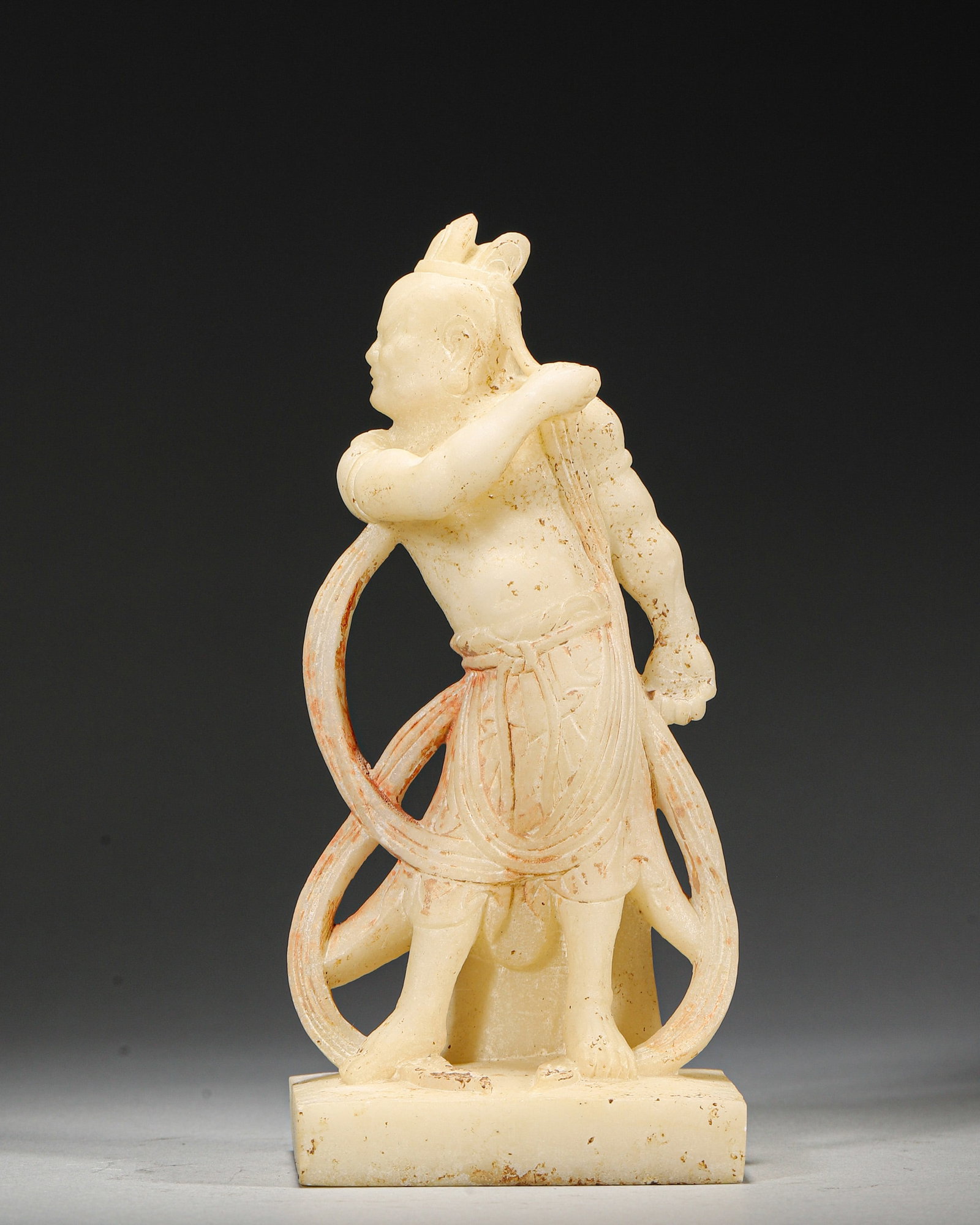 A WHITE JADE LOKAPALA FIGURE: A white jade figure of a Lokapala with dynamic drapery. L. 7 cm; W. 6 cm; Ht. 17 cm; Wt. 507 g.