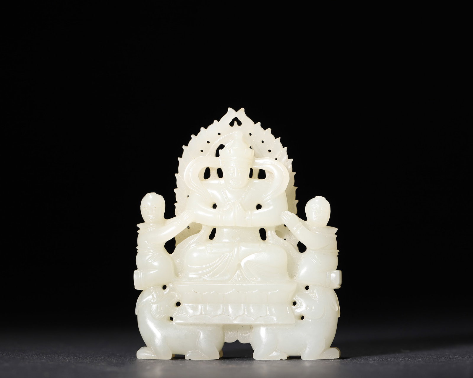 A WHITE JADE TIBETAN BUDDHIST BODHISATTVA GROUP: A white jade Tibetan Buddhist group centered by a Bodhisattva, with attendants, a double-lion base and an openwork flame-form halo. W. 5.5 cm; Ht. 7 cm; Wt. 69 g.