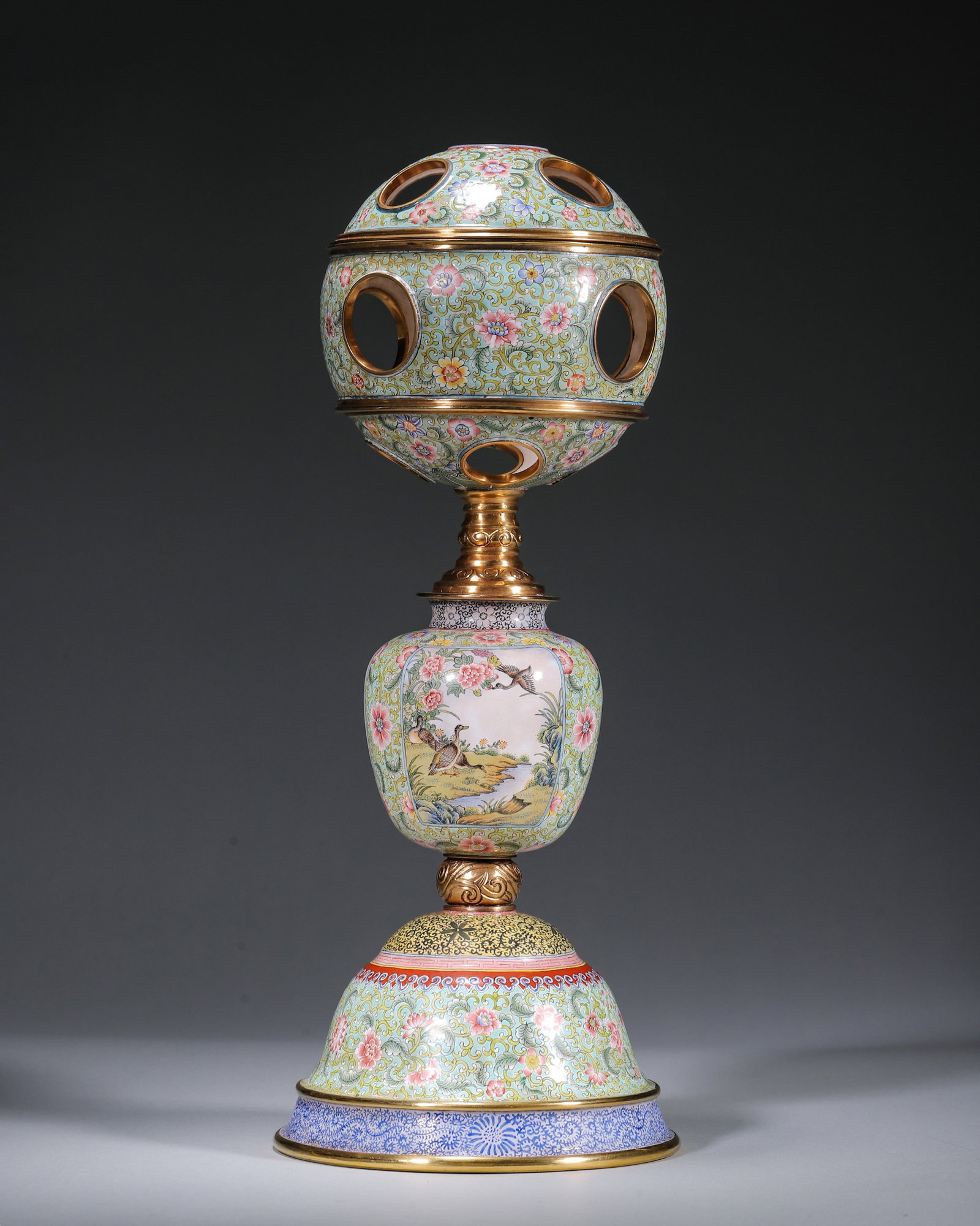 A GILT-BRONZE PAINTED-ENAMEL PIERCED SPHERICAL HAT STAND: A gilt-bronze painted-enamel hat stand with a pierced spherical top and detachable components, decorated with four bird-and-flower panels and scrolling lotus on a turquoise ground. The base bears a