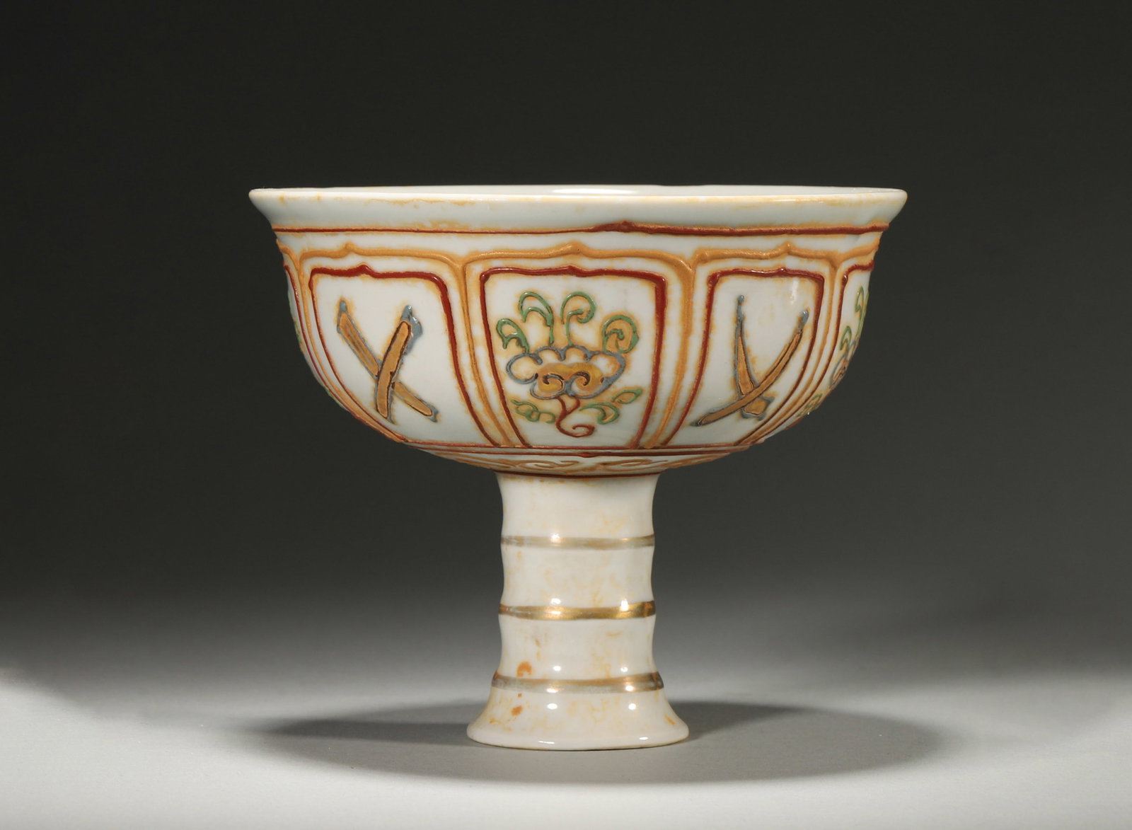 A WUCAI RELIEF-DECORATED 'EIGHT TREASURES' STEM CUP (1 of 6)