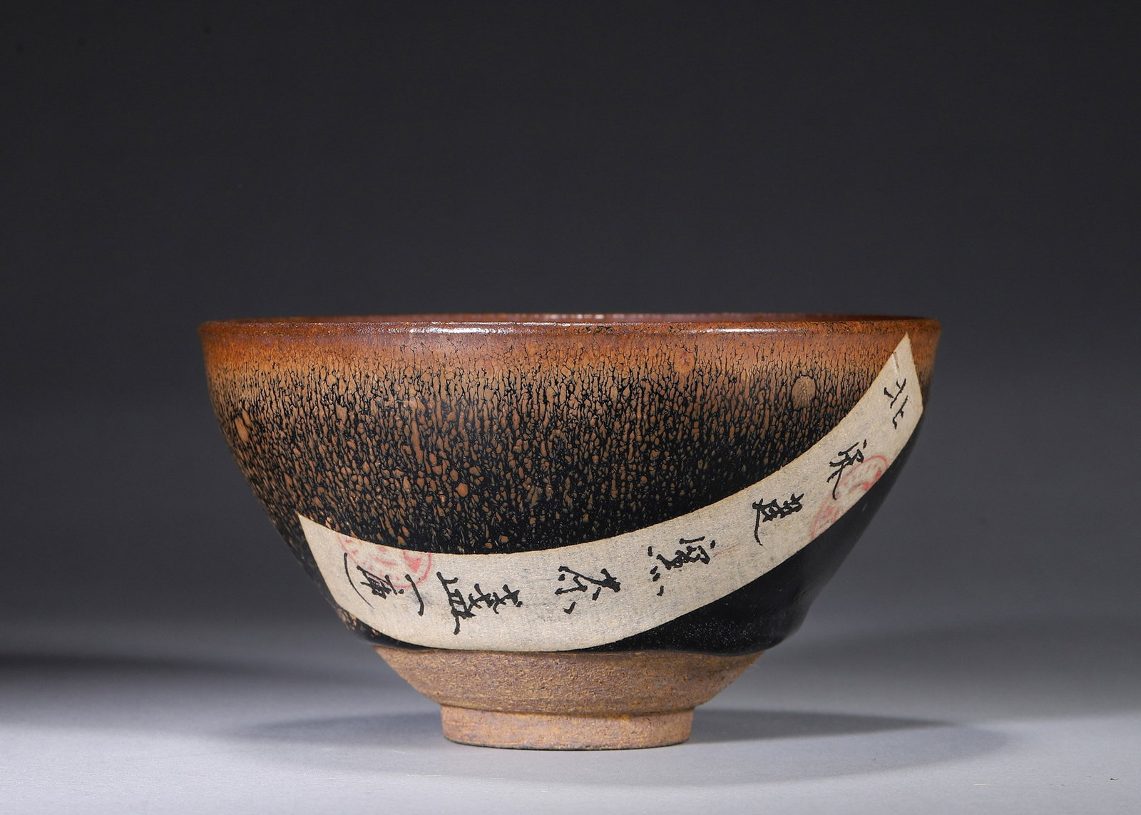 A 'HARE'S-FUR' JIAN-STYLE TEA BOWL: A Jian-style tea bowl with a deep body, covered in a dark glaze with fine golden hare's-fur streaks. The iron-brown base bears an incised mark. Diam. 13 cm; Ht. 7.5 cm. Note: With labels. By repute, a