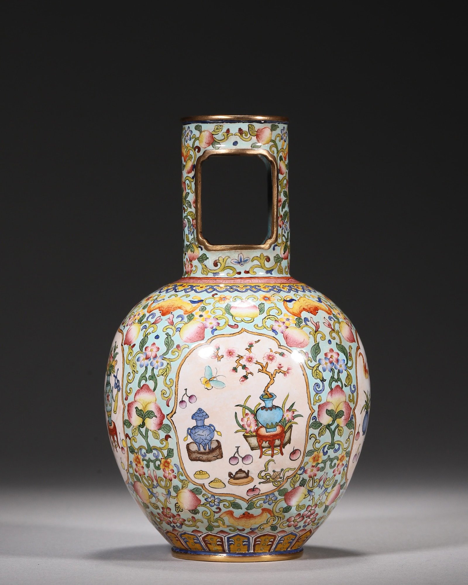 A COPPER-BODY PAINTED-ENAMEL VASE WITH ANTIQUITIES PANELS: A copper-body painted-enamel vase with a gilt rim and foot and square open handles, decorated with flowers and peaches and four panels of antiquities. The base bears a mark described in the source as