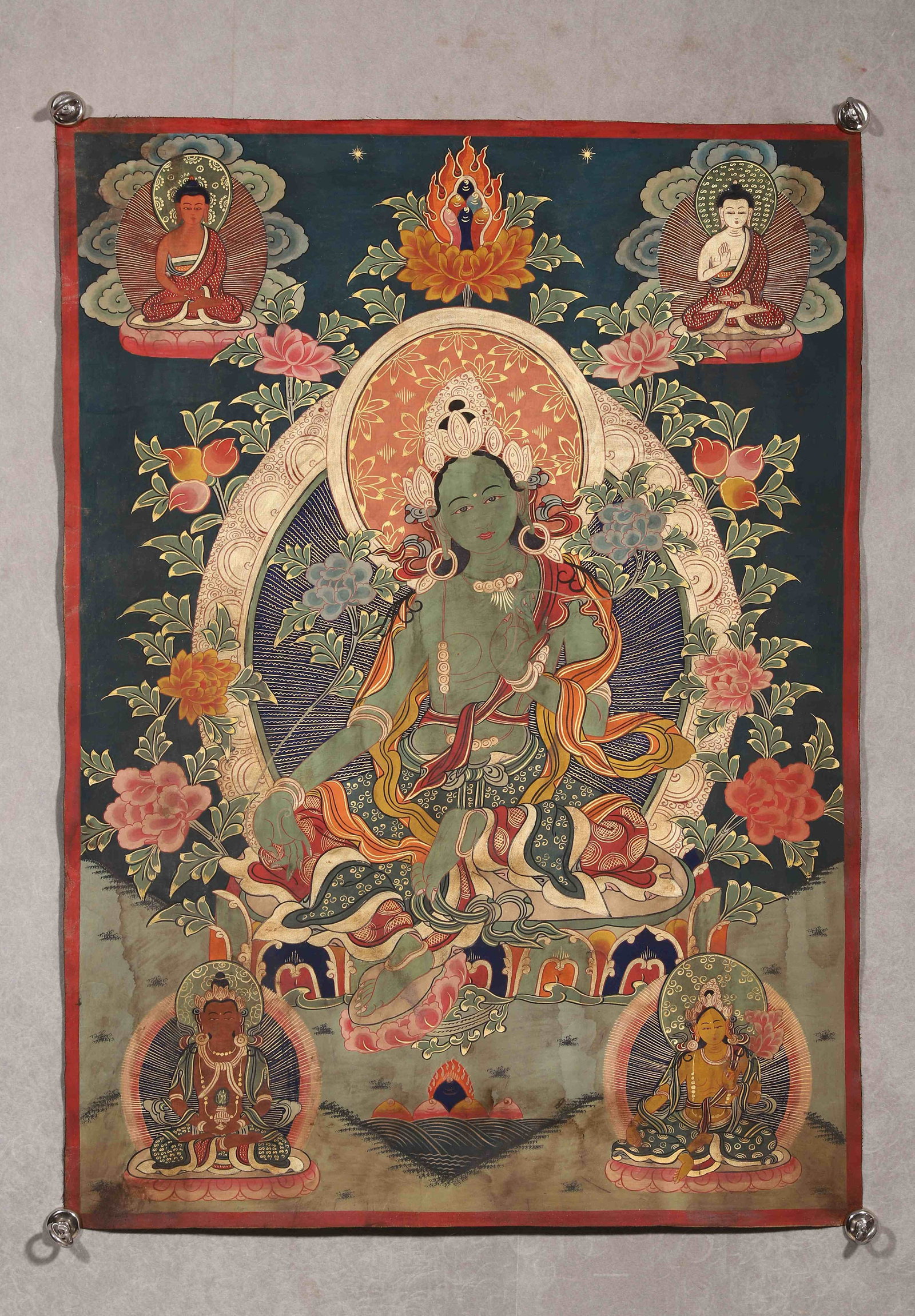A THANGKA OF GREEN TARA: A mineral-pigment thangka depicting Green Tara seated in lalitasana on a lotus throne, with the right hand in abhaya mudra and the left holding an utpala flower, surrounded by Buddhist figures and