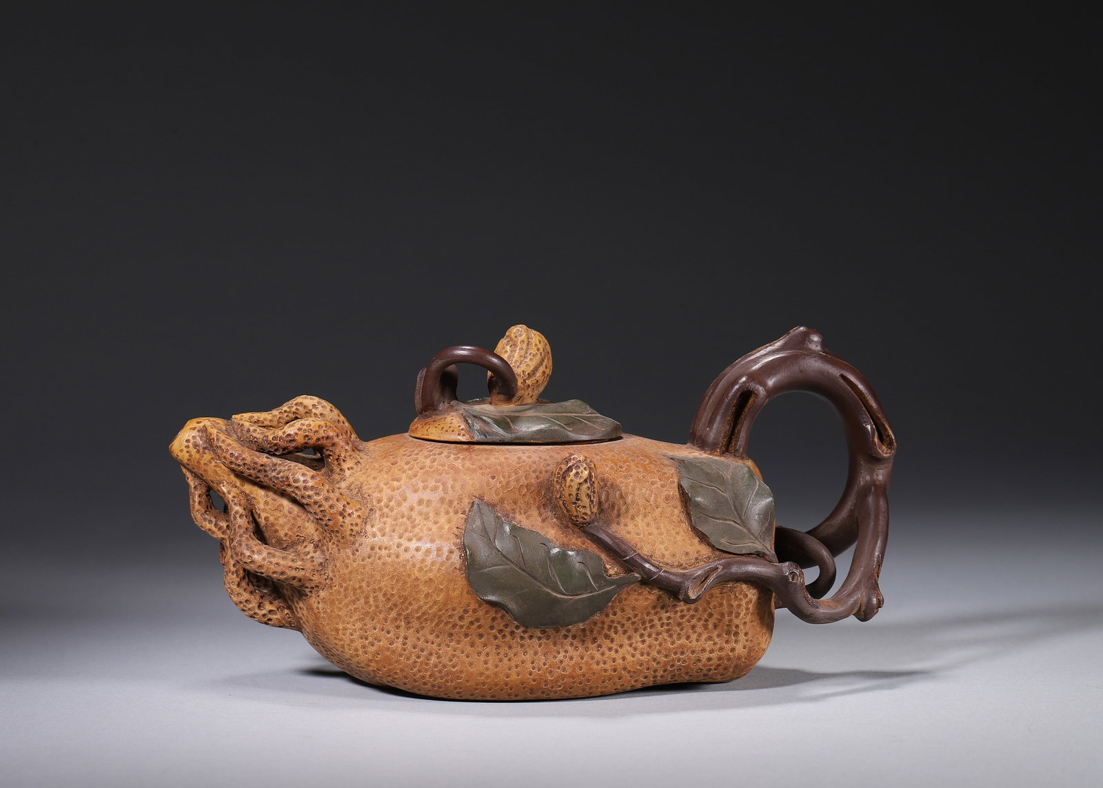 A ZISHA FINGERED-CITRON-FORM TEAPOT: A multi-toned zisha teapot modeled in the form of a fingered citron, with a textured surface, peanut-form finial and plant-form handle. The base and inner lid bear seals in the name of Jiang Rong. L. 