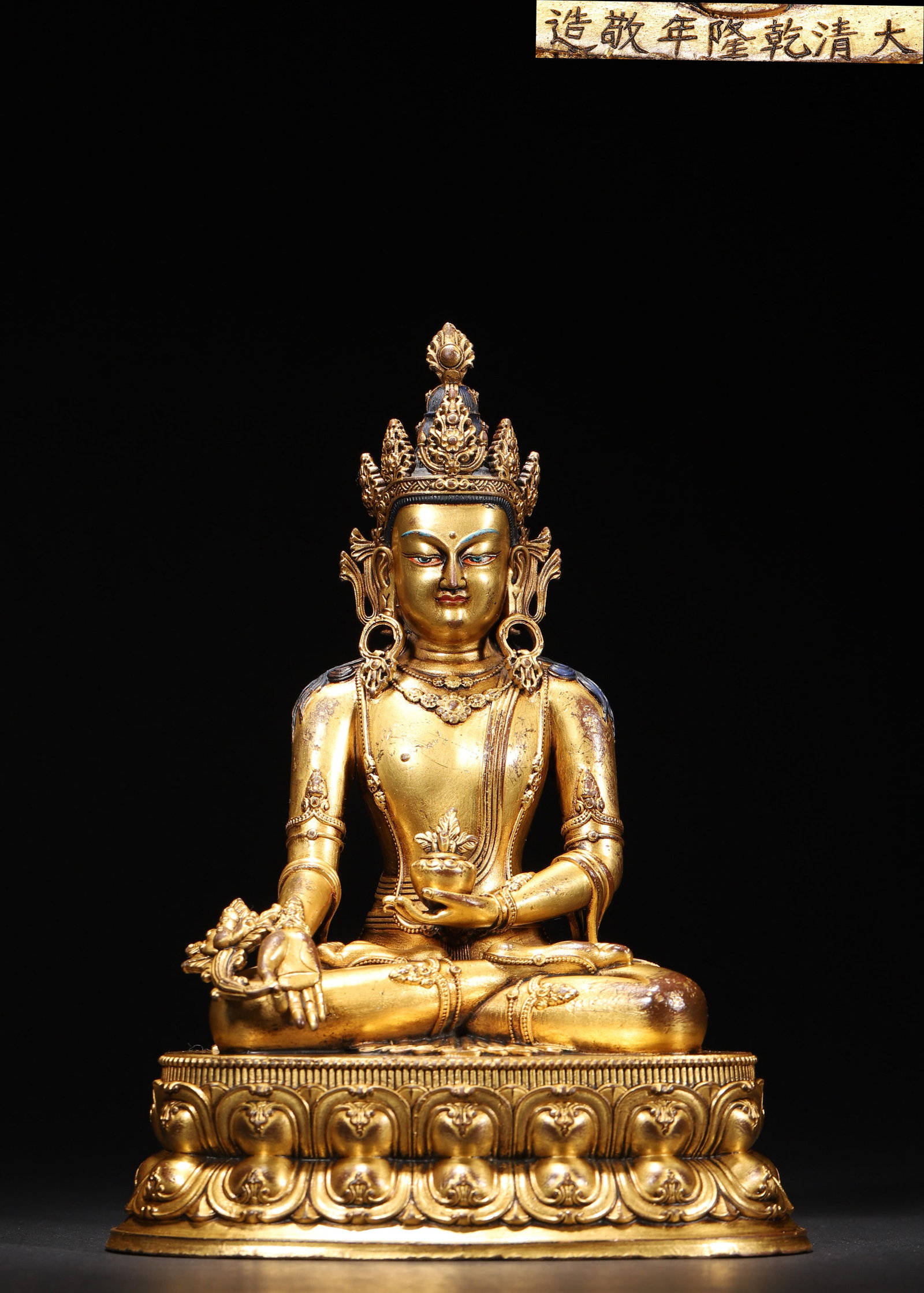 A GILT-BRONZE FIGURE OF BHAISAJYAGURU: A gilt-bronze figure of Bhaisajyaguru seated on a lotus base, the left hand holding a medicine vase and the right hand lowered in a gesture of offering. The base bears a reign mark described in the so