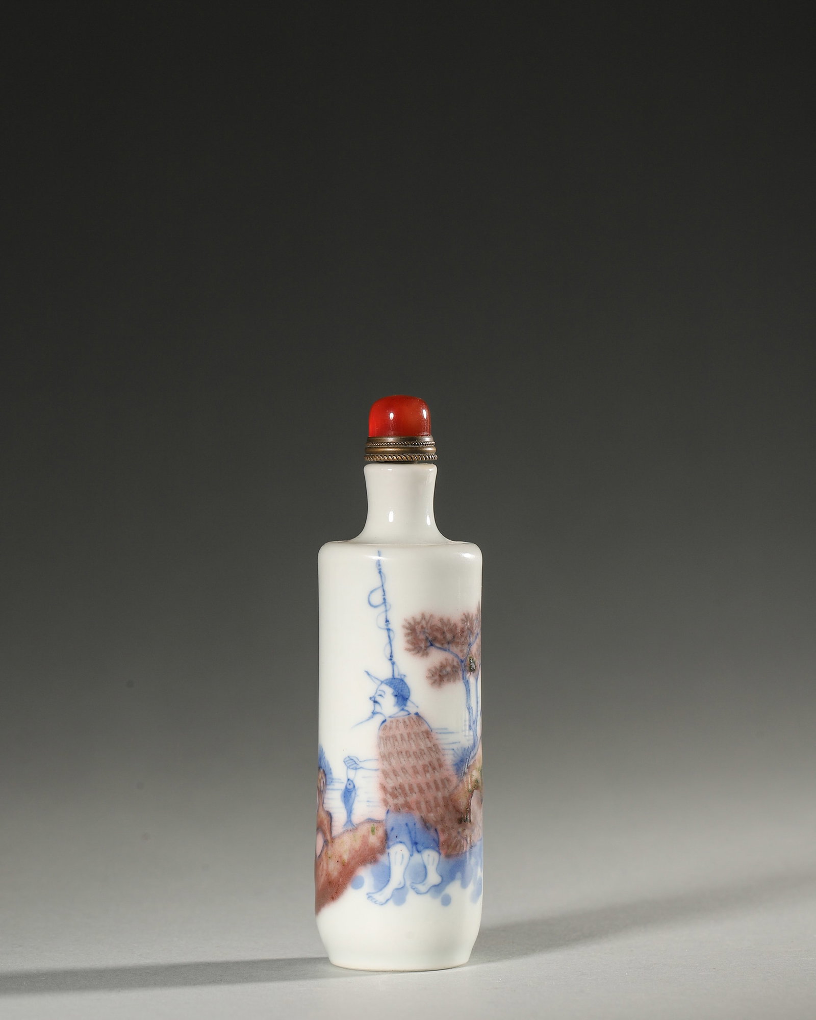 A BLUE-AND-WHITE AND UNDERGLAZE-RED FIGURAL PORCELAIN SNUFF BOTTLE: A blue-and-white and underglaze-red porcelain snuff bottle decorated with a figural scene. Diam. 3.3 cm; Ht. 10.5 cm.