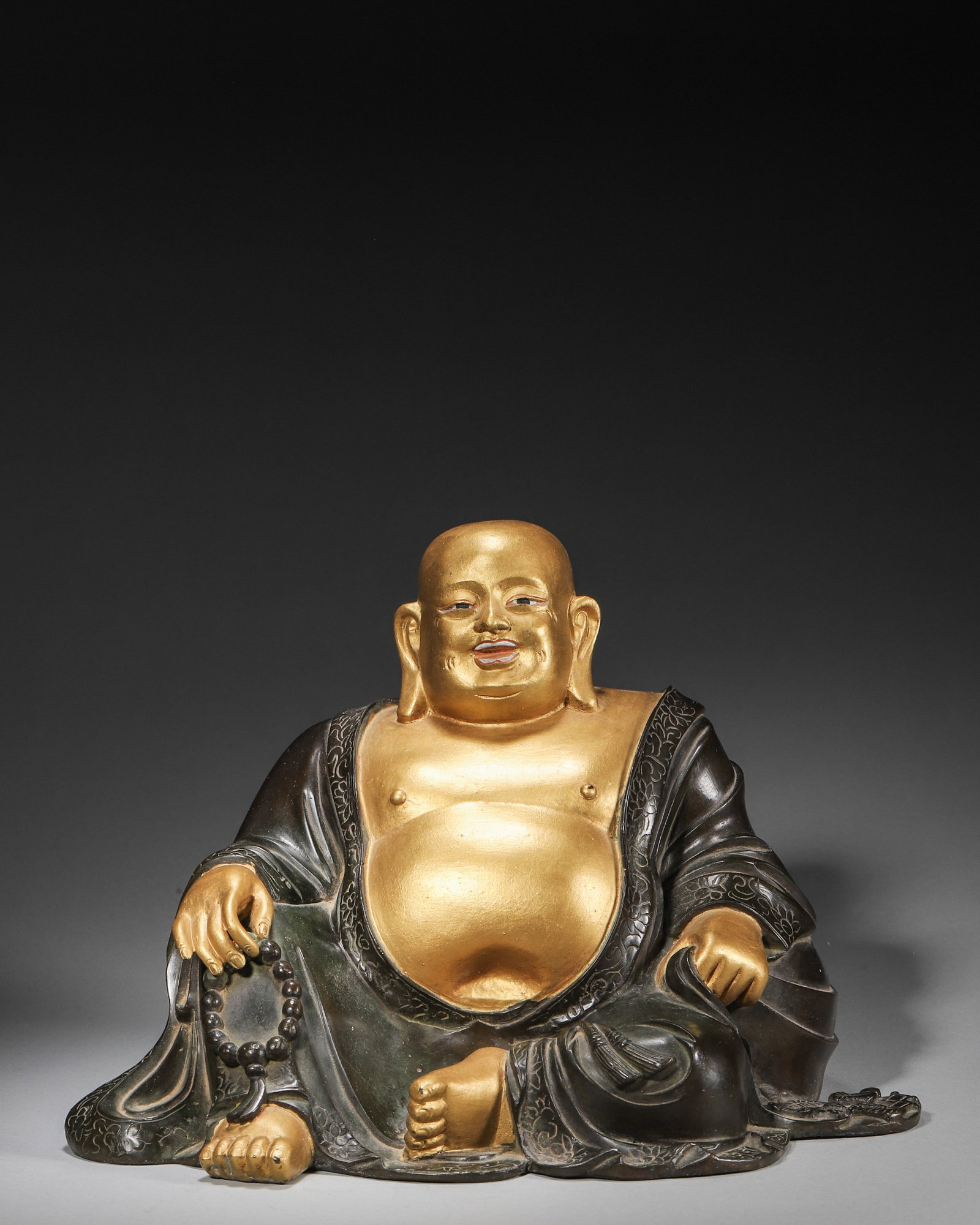 A GILT-BRONZE FIGURE OF MAITREYA: A gilt-bronze figure of Maitreya seated in a relaxed posture. W. 25 cm; Ht. 17 cm; Wt. 4,489 g.