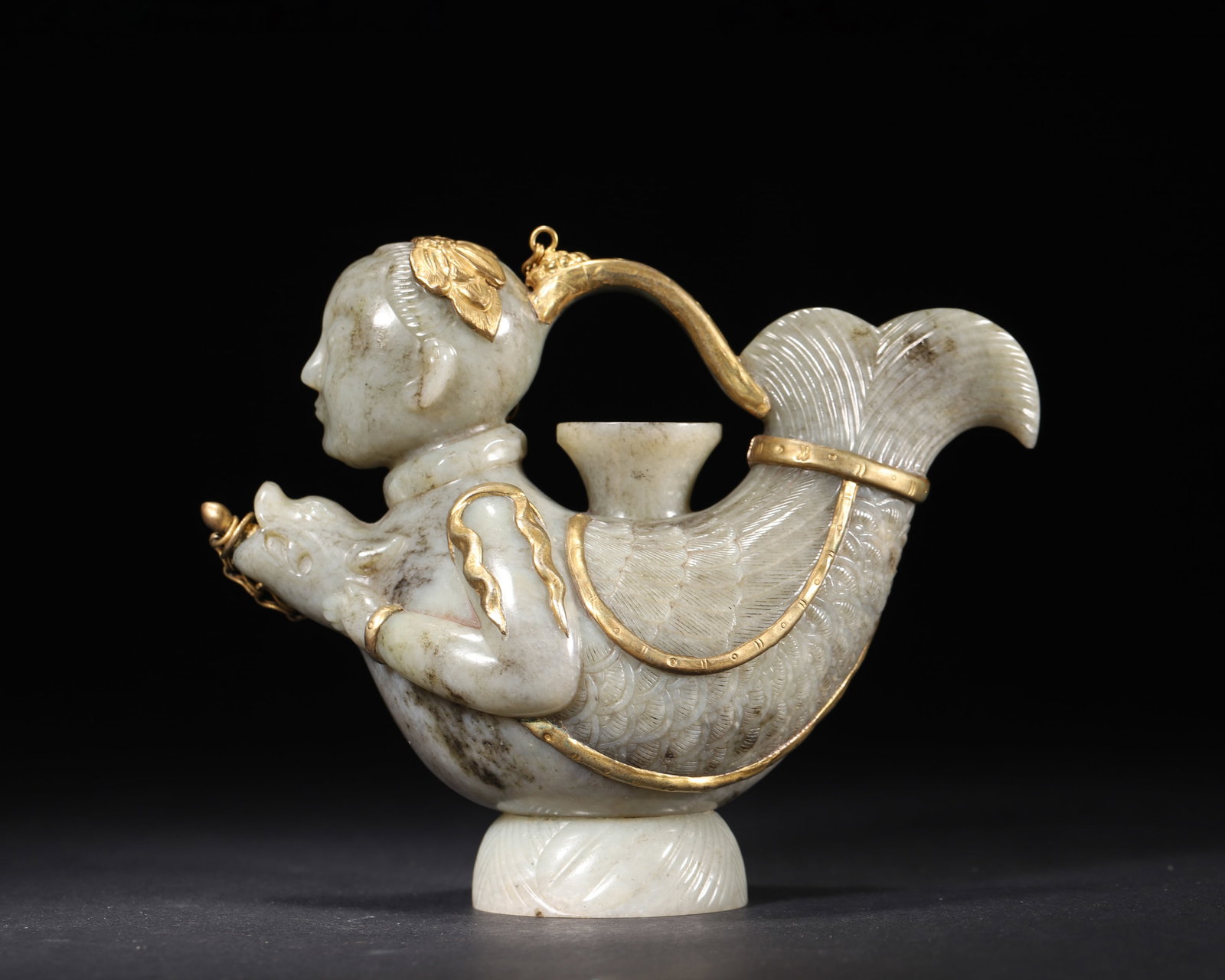 A GILT-MOUNTED JADE MAKARA-FORM EWER: A jade ewer with gilt mounts, carved in the form of a makara with a human head and fish-form body. L. 16 cm; W. 8 cm; Ht. 12 cm; Wt. 283 g.