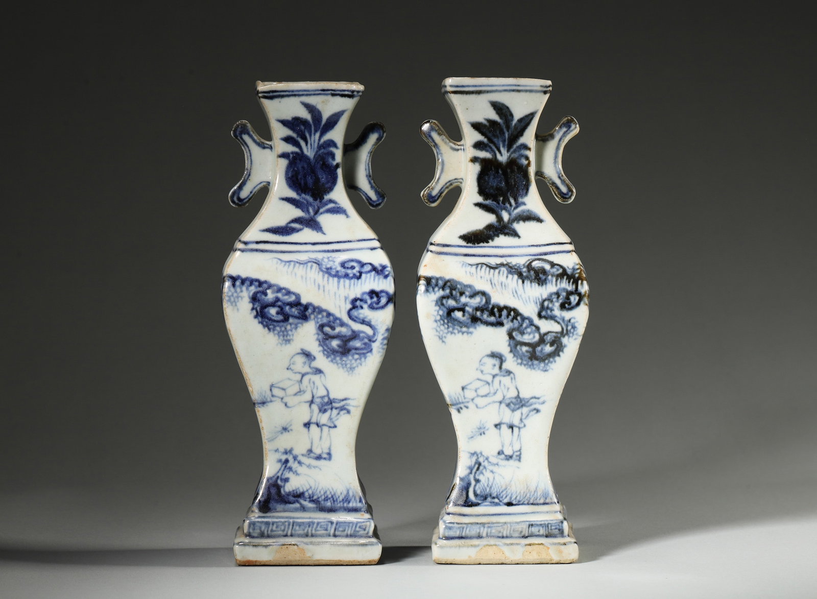 A PAIR OF BLUE-AND-WHITE SQUARE VASES WITH HALBERD-FORM HANDLES: A pair of square blue-and-white porcelain vases with halberd-form handles, painted with figures, fruit, clouds and landscapes. L. 7 cm; W. 5.5 cm; Ht. 20 cm.
