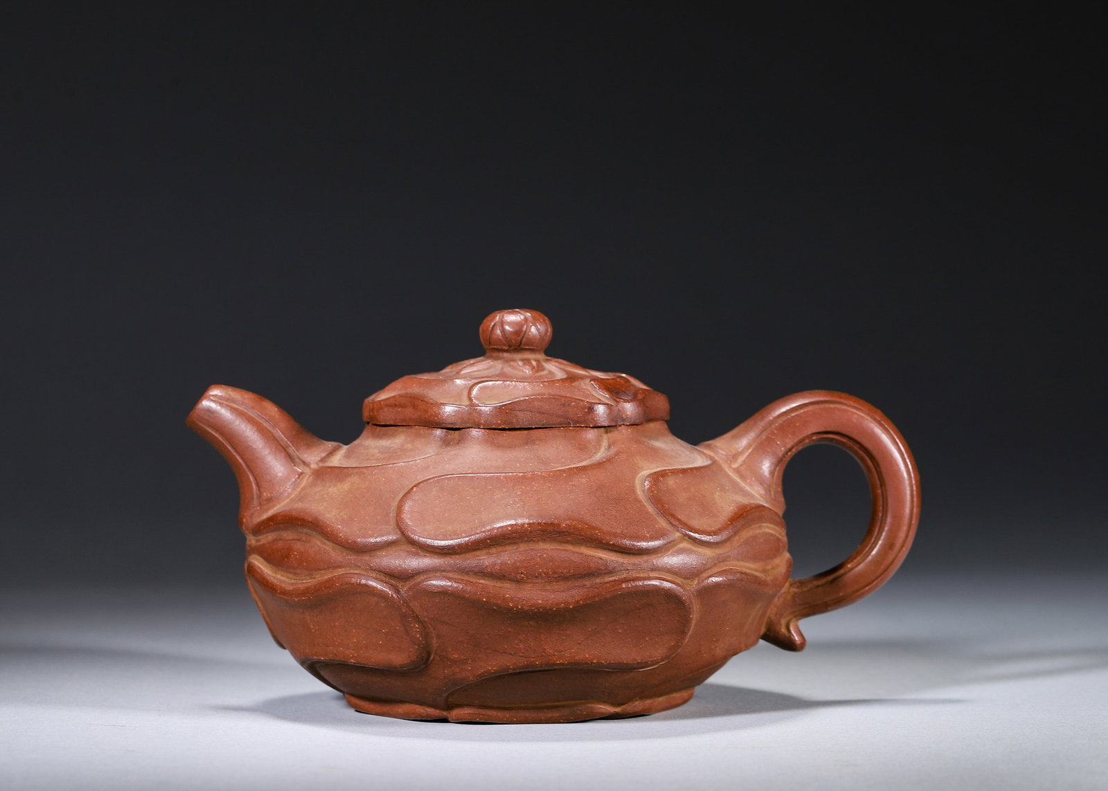 A ZISHA SUNFLOWER-FORM TEAPOT: A zisha teapot modeled with windswept sunflower petals and a flower-stamen finial. The base bears a seal in the name of Zhu Kexin. L. 16 cm; W. 12 cm; Ht. 8 cm.