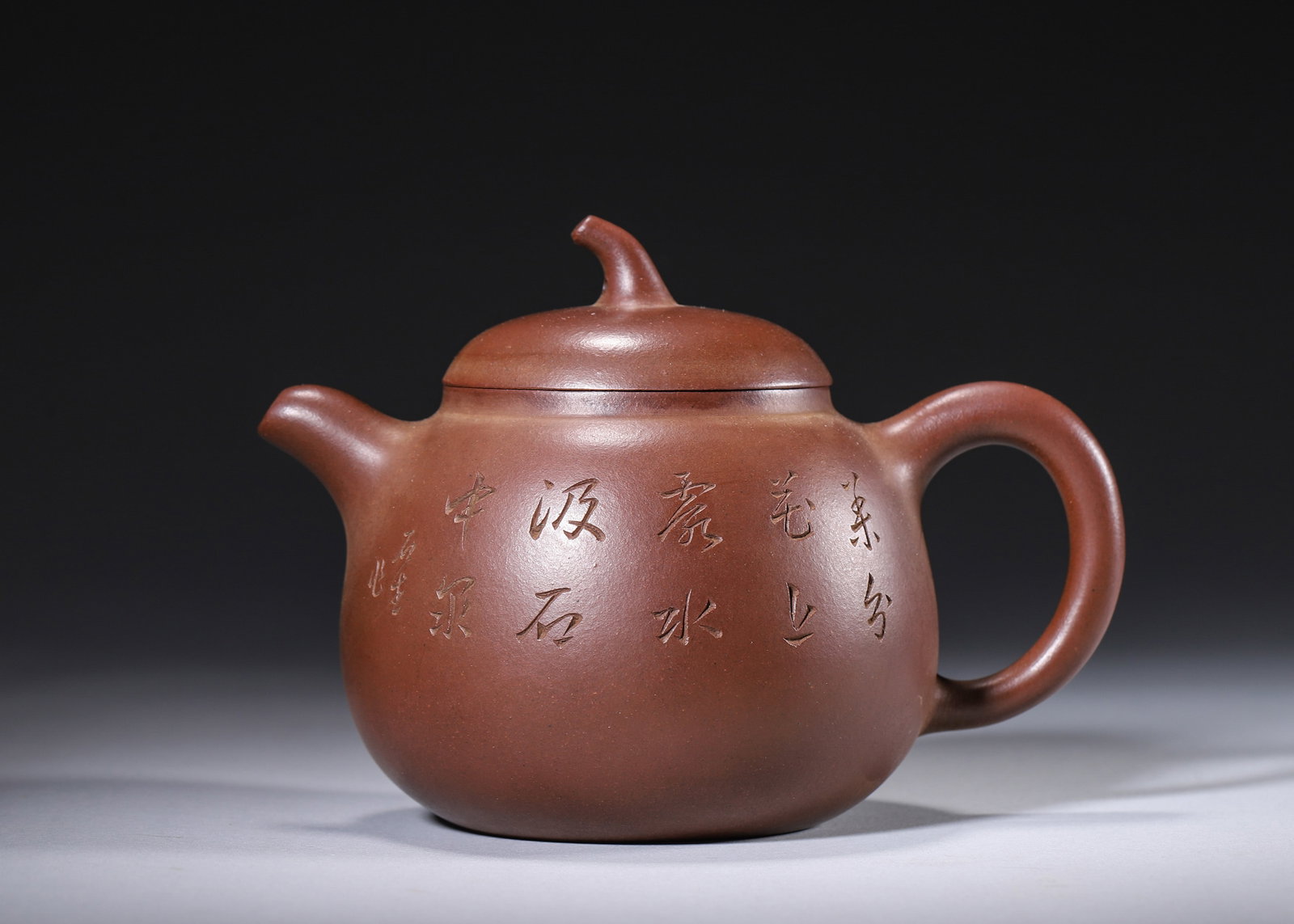 A ZISHA EGGPLANT-FORM TEAPOT WITH BIRD, PLUM AND INSCRIPTION: A zisha teapot with an eggplant-form finial, carved with a poem and a bird on a plum branch. The base bears a mark in the name of Gu Jingzhou. L. 16 cm; W. 11 cm; Ht. 11 cm.