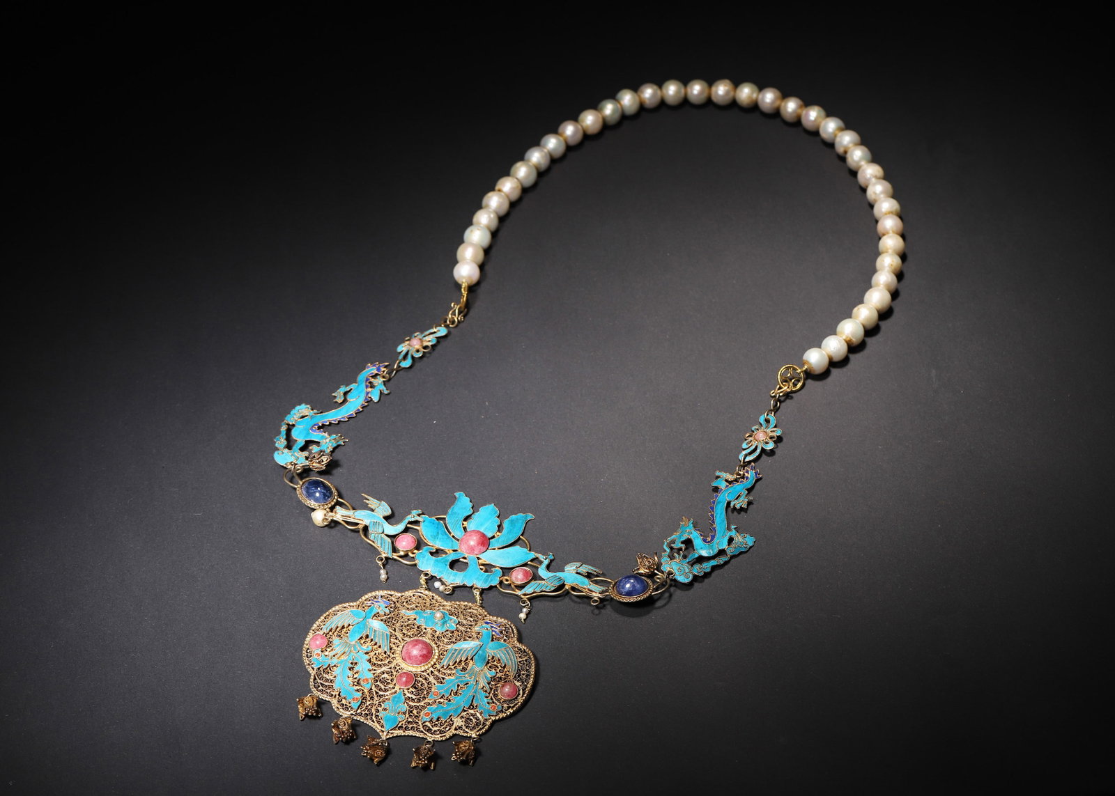 A GILT-SILVER KINGFISHER-FEATHER PHOENIX PENDANT NECKLACE WITH PEARL STRAND: A gilt-silver necklace with kingfisher-feather phoenix decoration, filigree work, colored-stone inlay, a pearl strand and a lock-form pendant with suspended bells. Dimensions: 36 x 18 cm; Wt. 133 g.