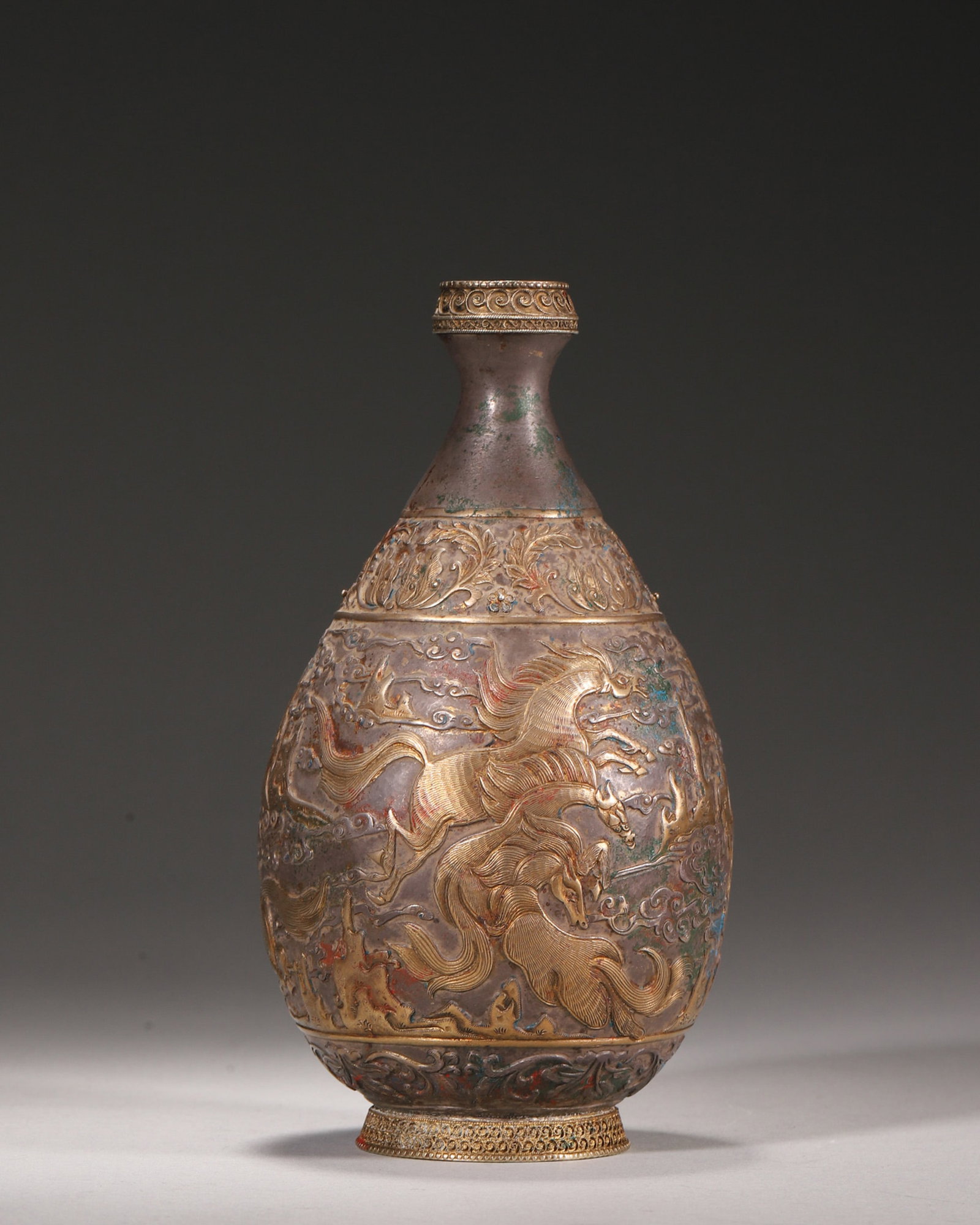 A PARTIALLY GILT SILVER 'HEAVENLY HORSE' FLASK: A pear-shaped silver flask with partial gilding, engraved with galloping horses amid clouds and floral scrolls to the neck and lower body. Diam. 8 cm; Ht. 16 cm; Wt. 212 g.