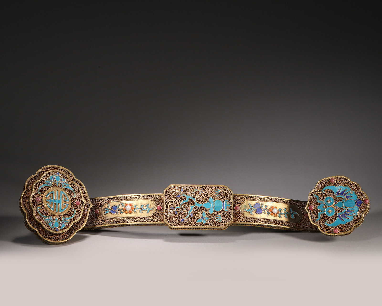 A SILVER-GILT FILIGREE RUYI SCEPTER WITH KINGFISHER-FEATHER AND COLORED-STONE INLAY: A silver-gilt filigree ruyi scepter decorated with kingfisher-feather shou, bat and gourd motifs, with pearls and red colored-stone inlay. L. 45 cm; W. 10.5 cm; Wt. 687 g.