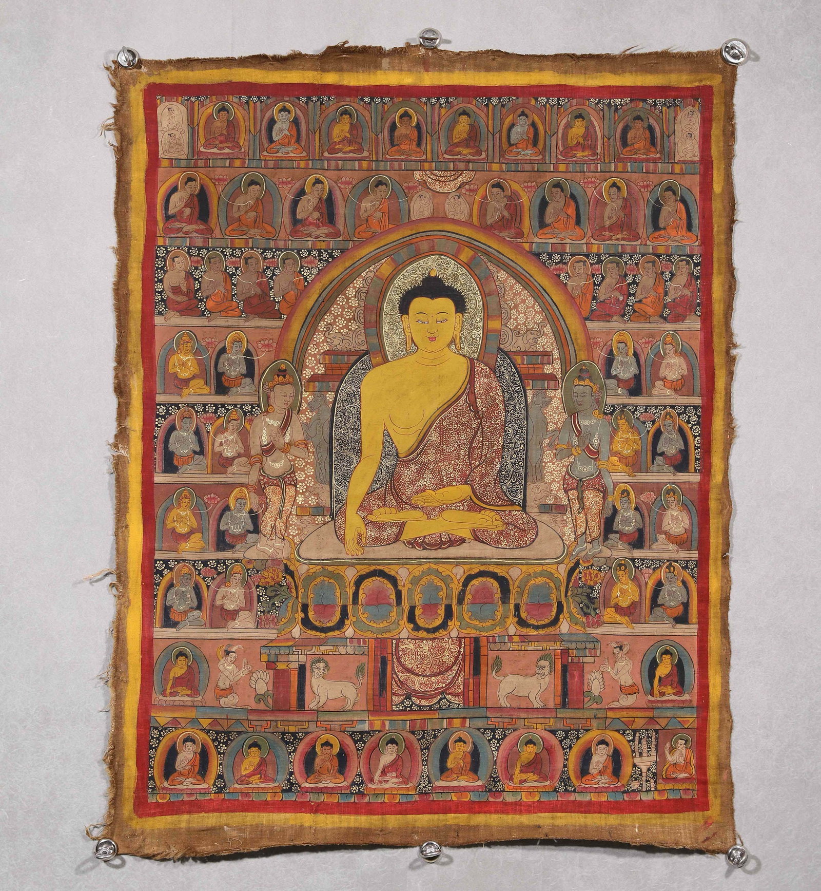 A THANGKA OF SHAKYAMUNI BUDDHA: A mineral-pigment thangka depicting Shakyamuni Buddha seated in lotus posture with the earth-touching mudra, flanked by bodhisattvas and surrounded by rows of Buddhist figures. The reverse bears red