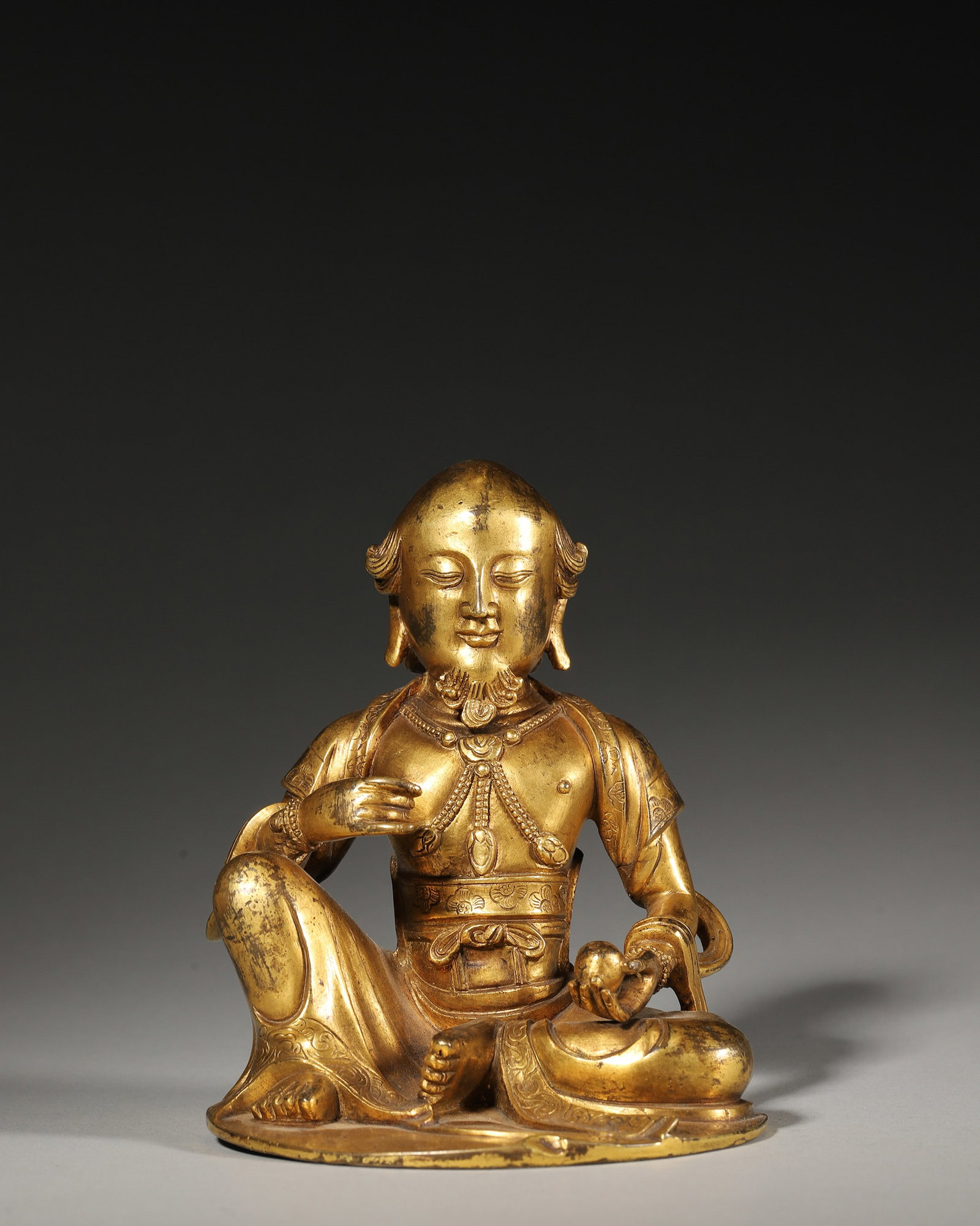 A GILT-BRONZE SEATED FIGURE: A gilt-bronze seated figure. W. 10 cm; Ht. 11.5 cm; Wt. 1,063 g.