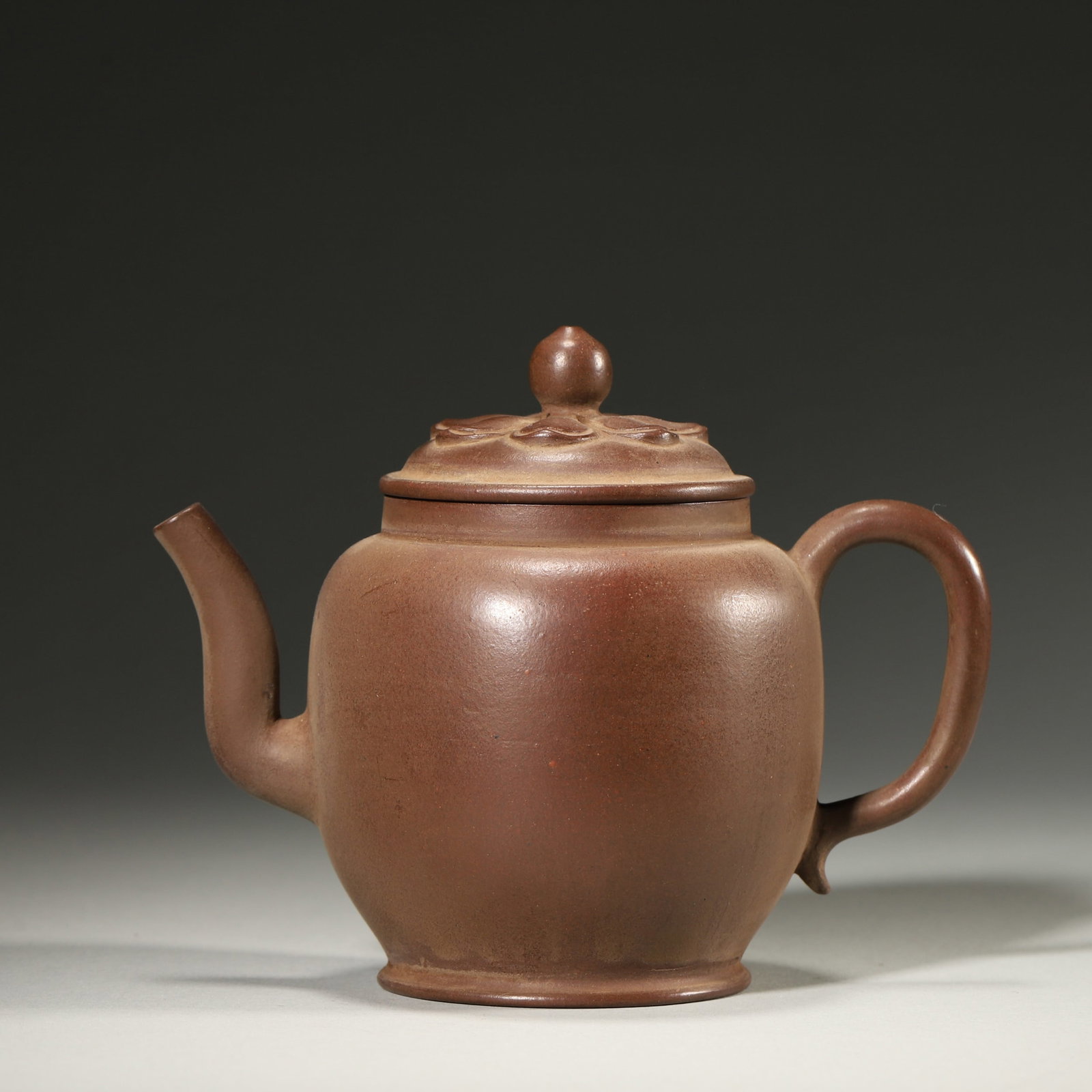 A ZISHA PALACE-LANTERN-FORM TEAPOT WITH LOTUS-PETAL COVER: A purple-clay zisha teapot of palace-lantern form, the cover molded with lotus petals and surmounted by a bead-form finial. L. 13.5 cm; W. 8.5 cm; Ht. 11 cm.