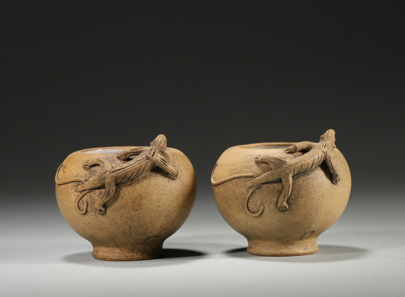 A PAIR OF DUANNI ZISHA WASHERS WITH CHILONG: A pair of round duanni zisha washers with ring feet and relief chilong to the rims, with white-glazed interiors. Diam. 6.5 cm; Ht. 5 cm.