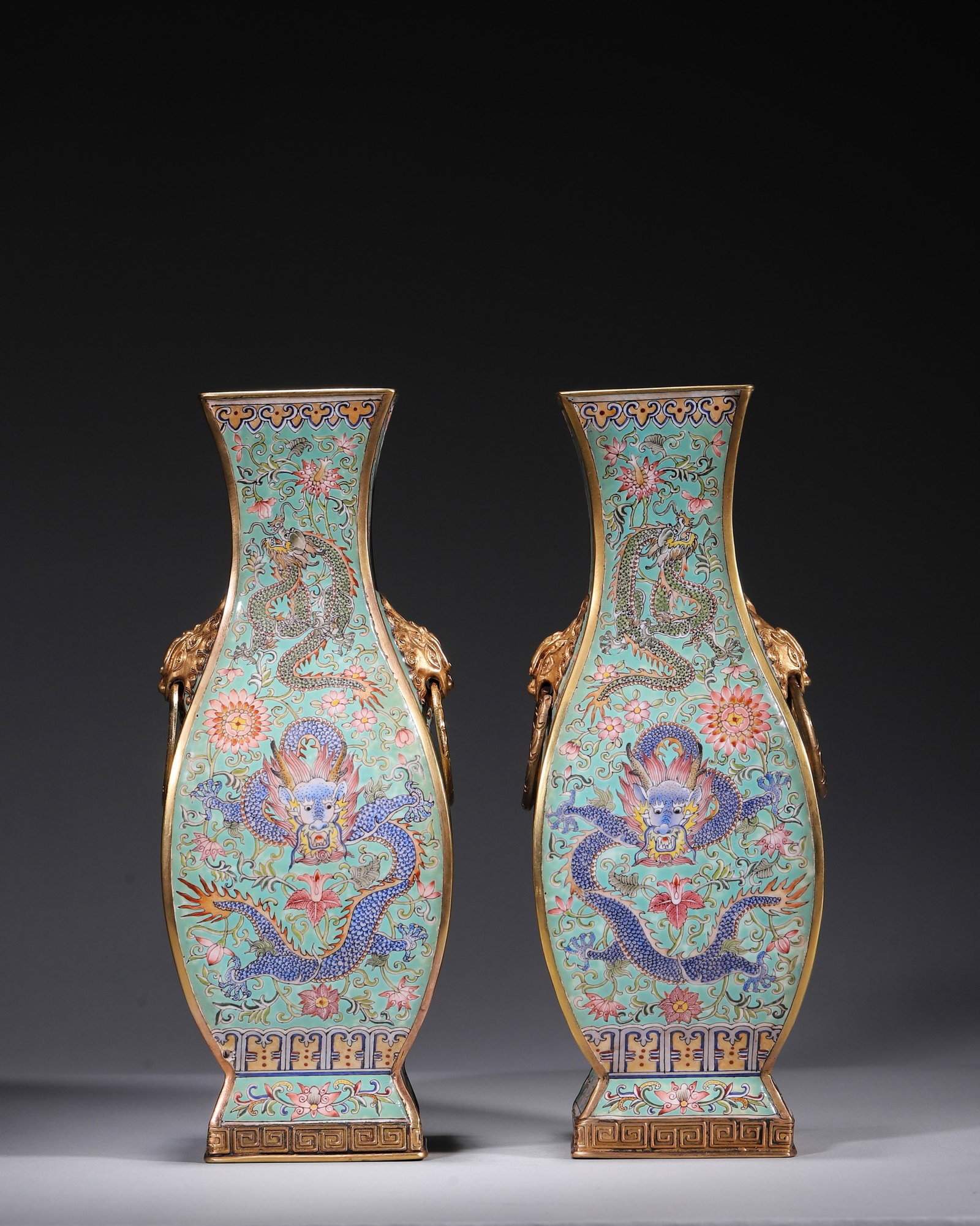 A PAIR OF PAINTED-ENAMEL BRONZE 'DRAGON AND PHOENIX' VASES: A pair of flattened square painted-enamel bronze vases with gilt rims and bases and lion-head ring handles, decorated with dragons, phoenixes and lotus scrolls on a turquoise ground. The bases bear si