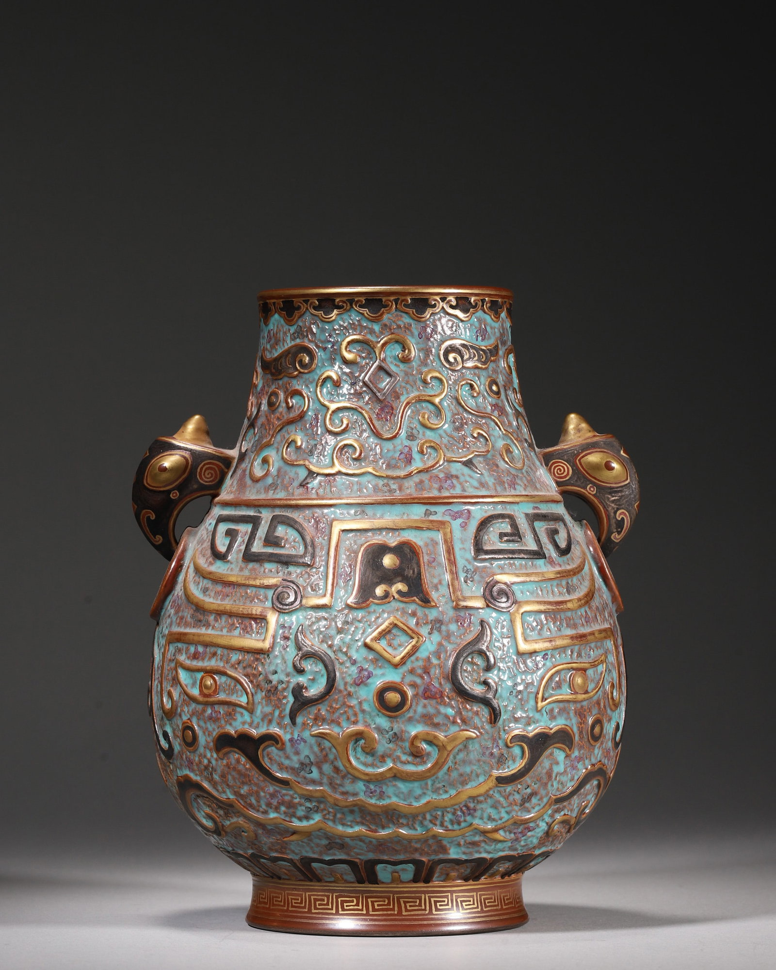A BRONZE-IMITATION-GLAZED RELIEF 'TAOTIE' PORCELAIN ZUN: A porcelain zun with beast-head ring handles, covered in a speckled turquoise bronze-imitation glaze and decorated in relief with archaistic taotie motifs, with gilt and silver-colored details and key