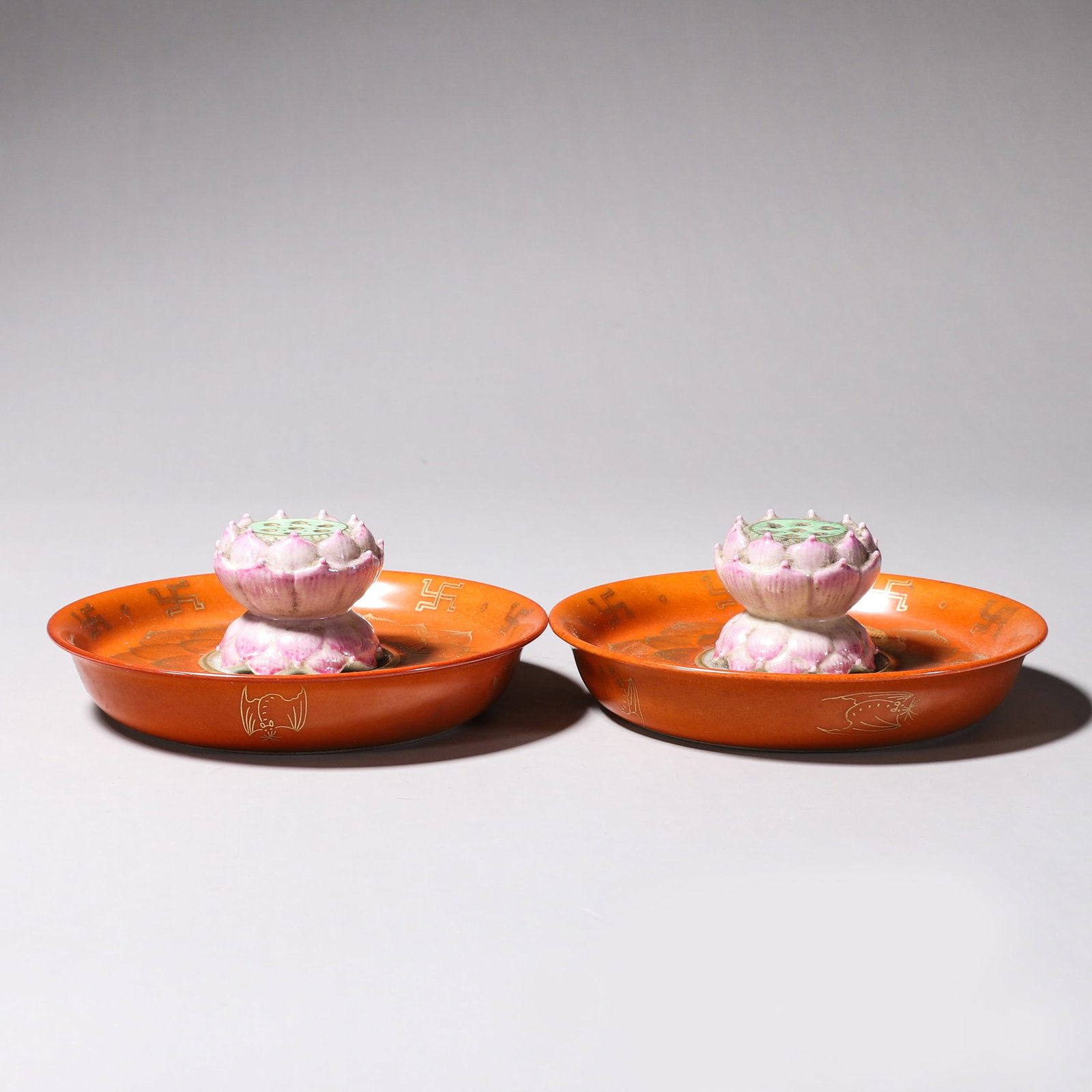 A PAIR OF IRON-RED AND GILT FAMILLE-ROSE LOTUS-FORM INCENSE HOLDERS: A pair of famille-rose incense holders, each with an iron-red and gilt tray supporting a pierced lotus-bud form. Diam. 11.3 cm; Ht. 4 cm; Wt. 140 g. Note: By repute, associated with Buddhist incense