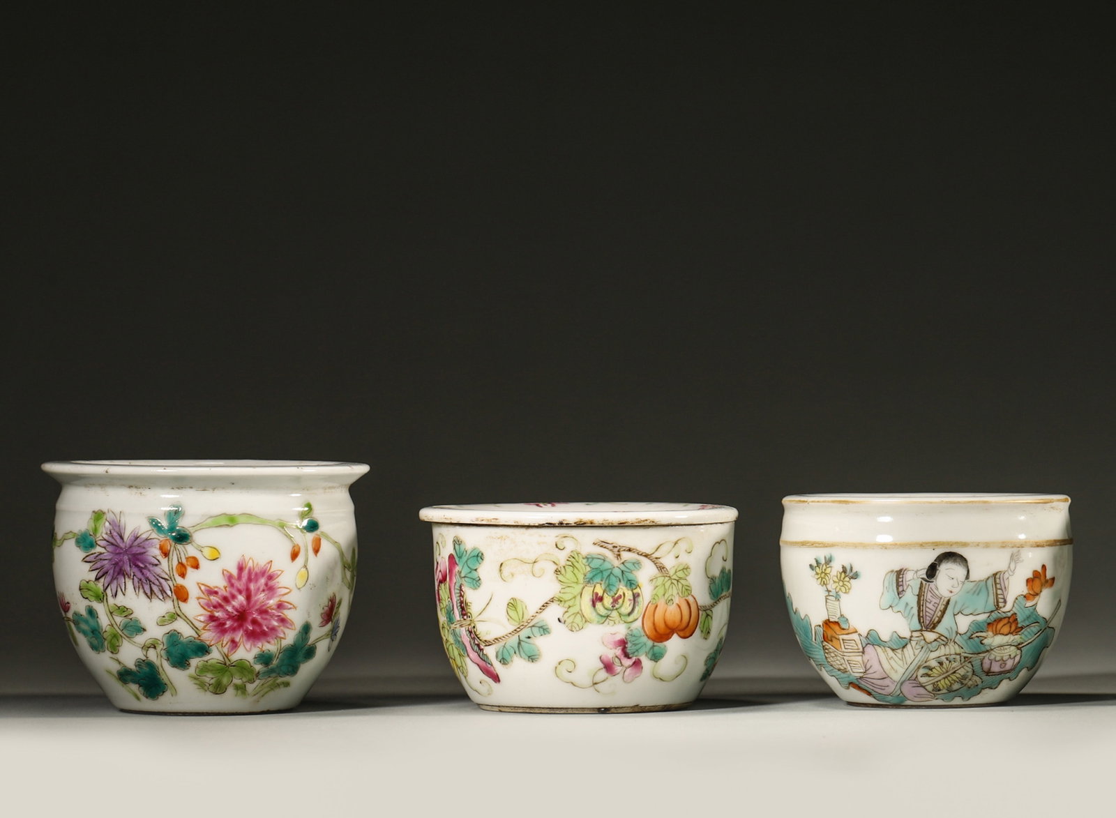 A SET OF THREE FAMILLE-ROSE CRICKET JARS: A set of three famille-rose porcelain cricket jars decorated with flowers, insects and figural scenes. Diam. 9 cm; Ht. 7 cm.