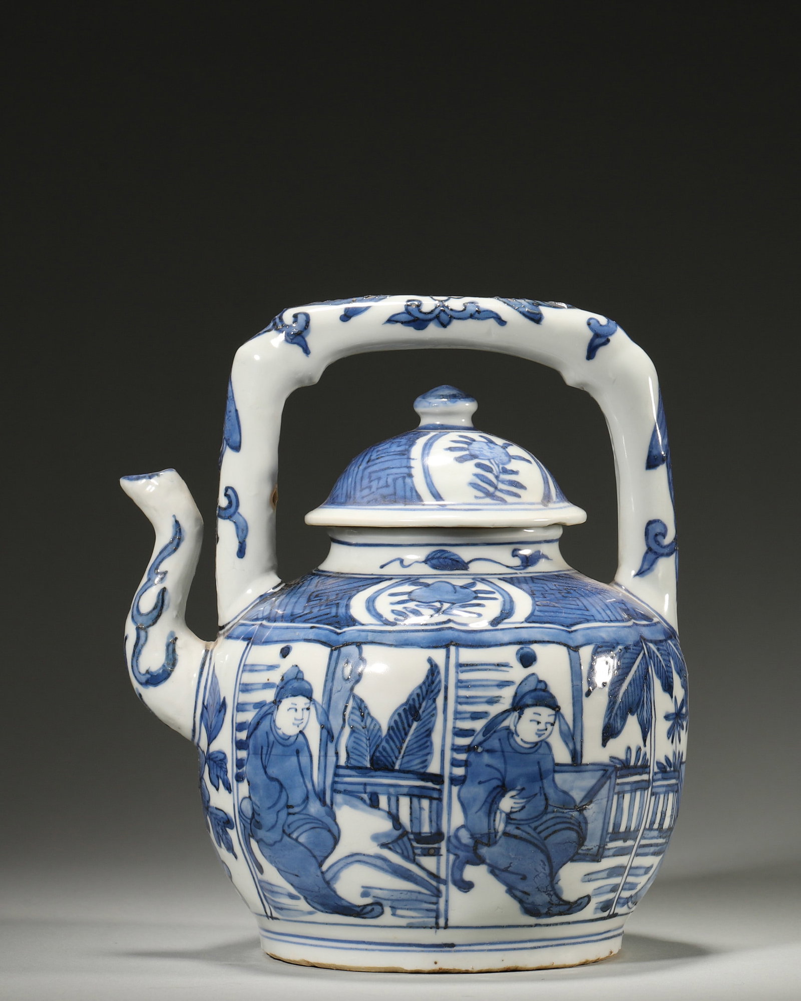A BLUE-AND-WHITE FIGURAL EWER WITH OVERHEAD HANDLE: A blue-and-white porcelain ewer with an overhead handle and cover, painted with a literati scene in a courtyard. W. 17 cm; Ht. 20 cm. Note: By repute, associated with wine or water service.