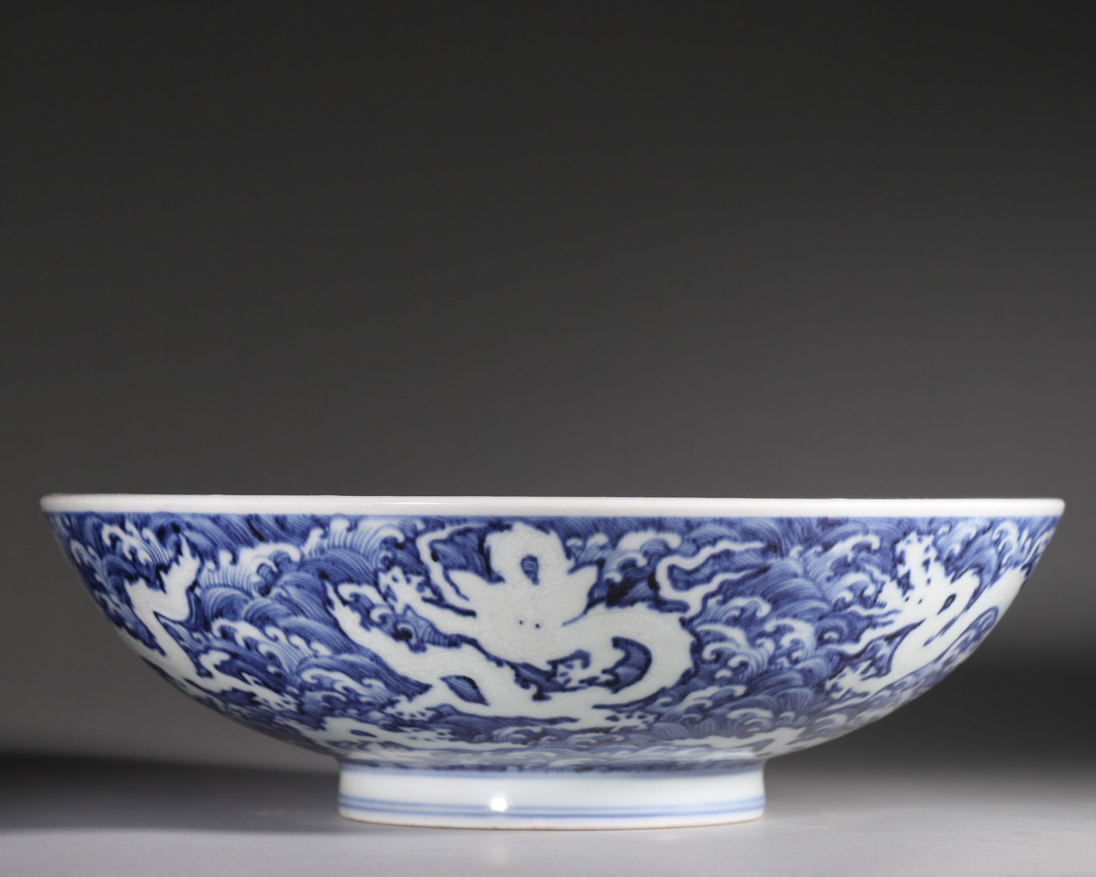 A BLUE-AND-WHITE 'RESERVED-WHITE DRAGONS AND WAVES' BOWL (1 of 11)