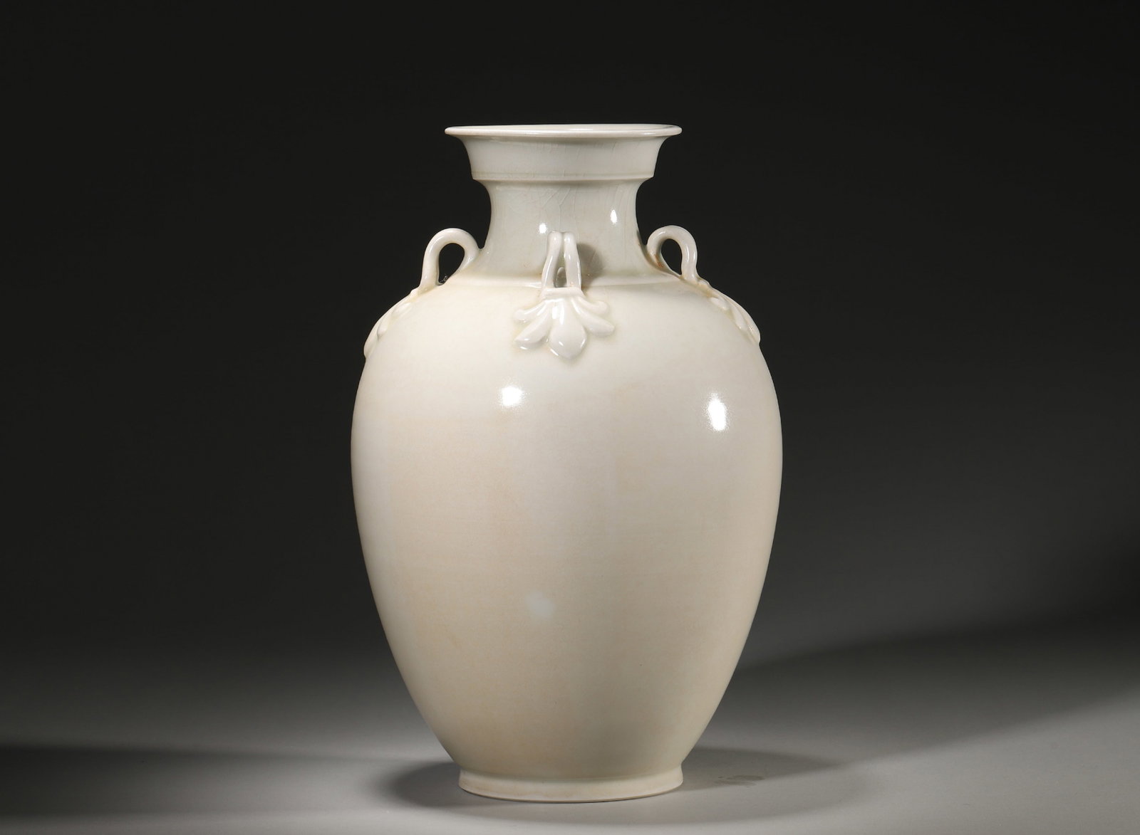A WHITE-GLAZED VASE WITH FOUR LOOP HANDLES: A white-glazed porcelain vase with four loop handles and relief lotus decoration to the shoulder. The base bears a two-character mark reading 'Hanlin'. Diam. 18 cm; Ht. 28 cm.
