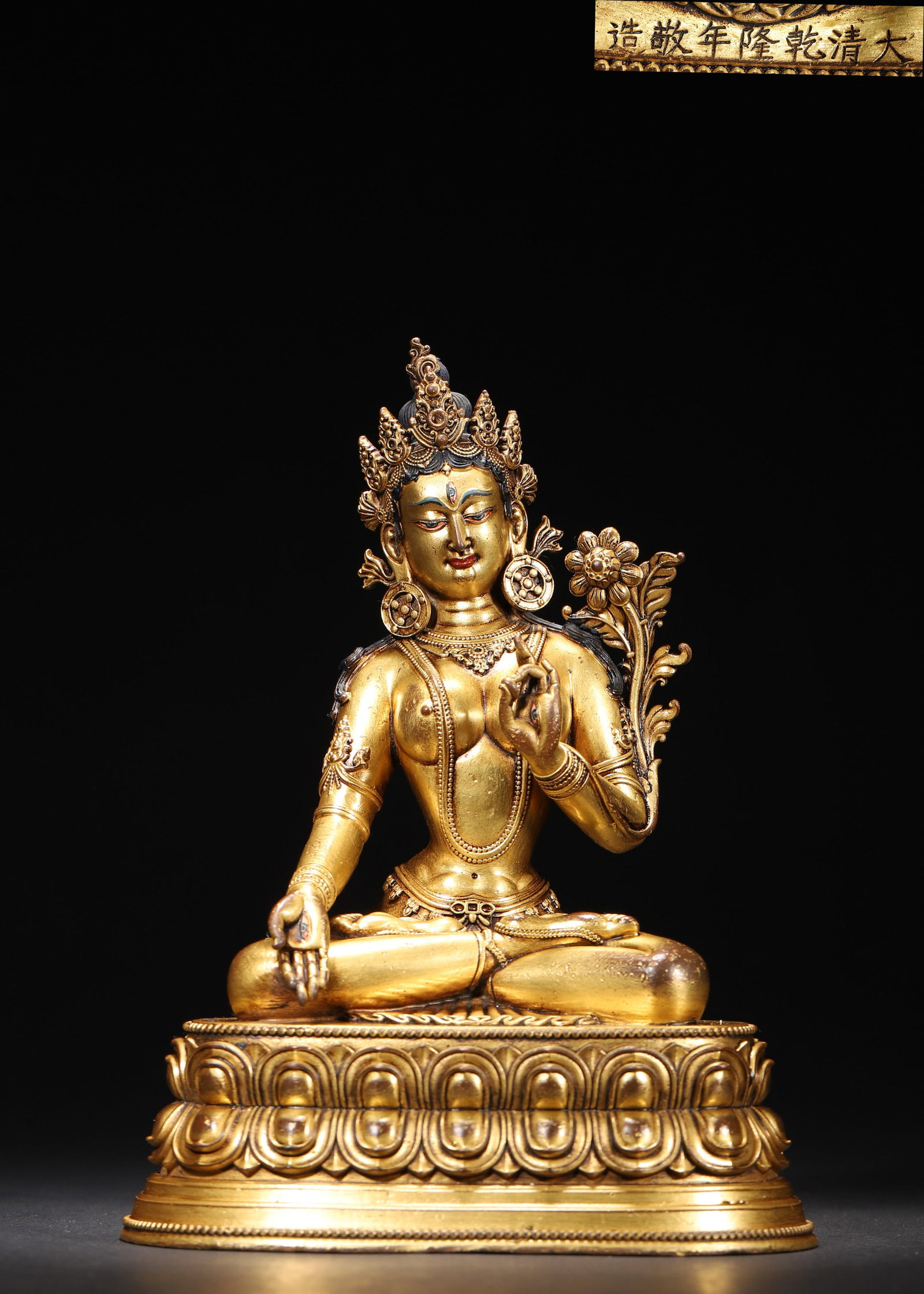 A GILT-BRONZE FIGURE OF WHITE TARA: A gilt-bronze figure of White Tara seated on a lotus base. The figure bears an inscription reading 'Da Qing Qianlong Nian Jing Zao'. L. 16 cm; W. 12 cm; Ht. 22 cm; Wt. 1,650 g.