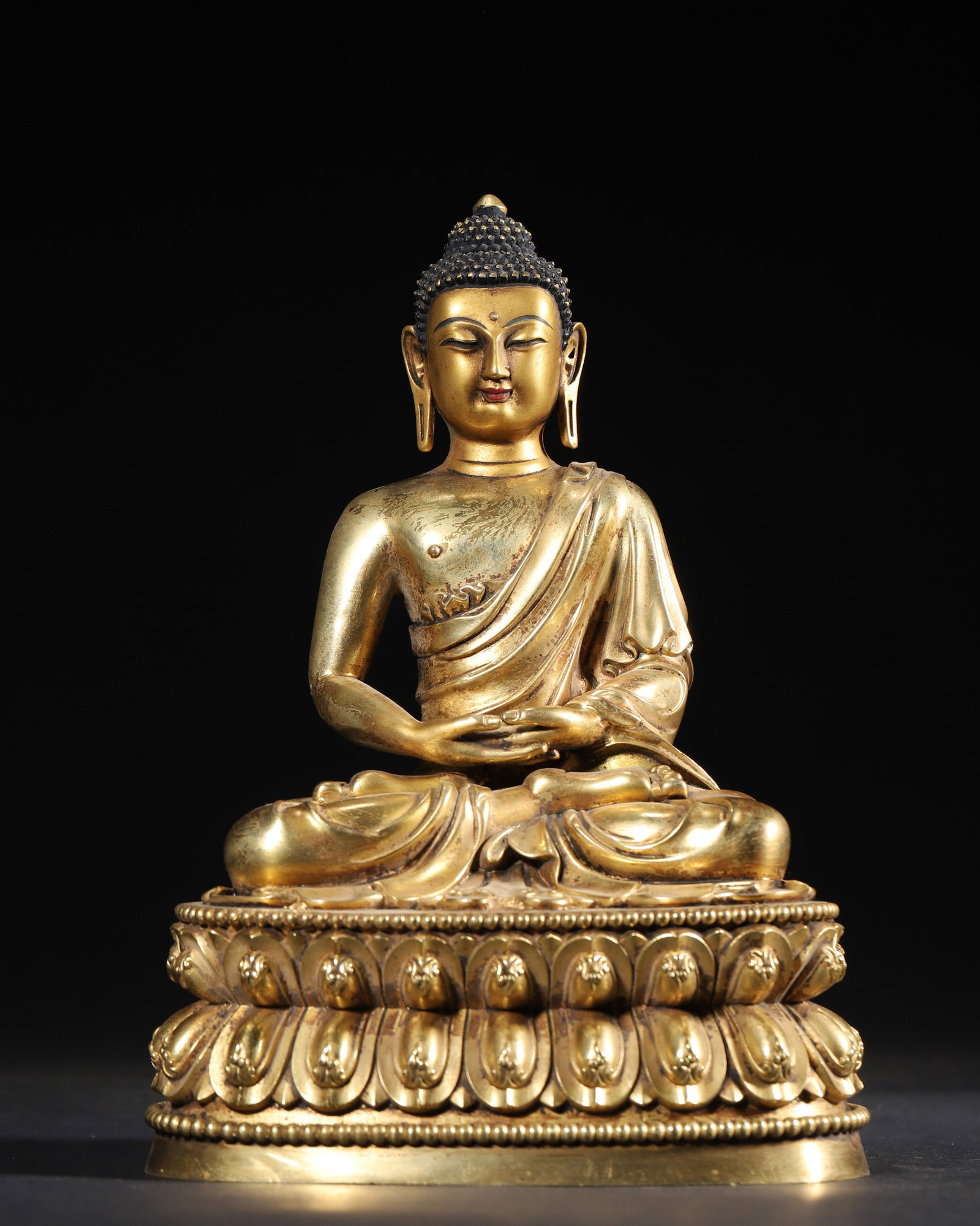 A GILT-BRONZE FIGURE OF AMITABHA: A gilt-bronze figure of Amitabha seated on a lotus base, with a crossed-vajra motif to the base. L. 15 cm; W. 11 cm; Ht. 22 cm; Wt. 1,459 g.