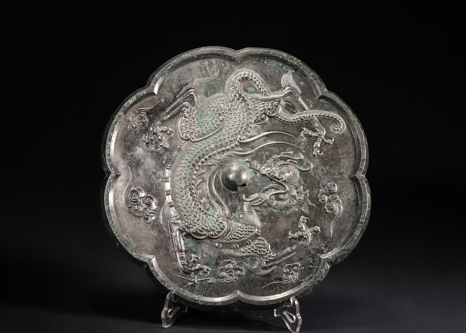 A LOBED BRONZE 'DRAGON AND CLOUD' MIRROR: A lobed bronze mirror decorated in high relief with a dragon amid clouds. Diam. 20 cm.