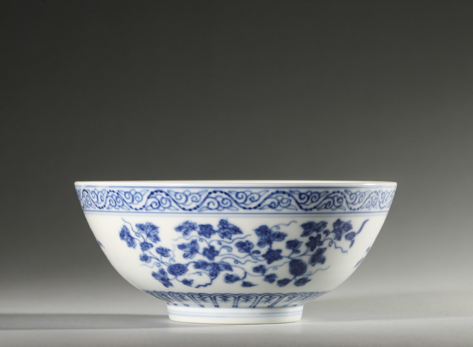 A BLUE-AND-WHITE 'THREE FRUITS' BOWL: A blue-and-white porcelain bowl painted to the exterior with pomegranate, peach and grape motifs and to the interior with a dragon medallion. The base bears a mark described in the source as Xianfeng.
