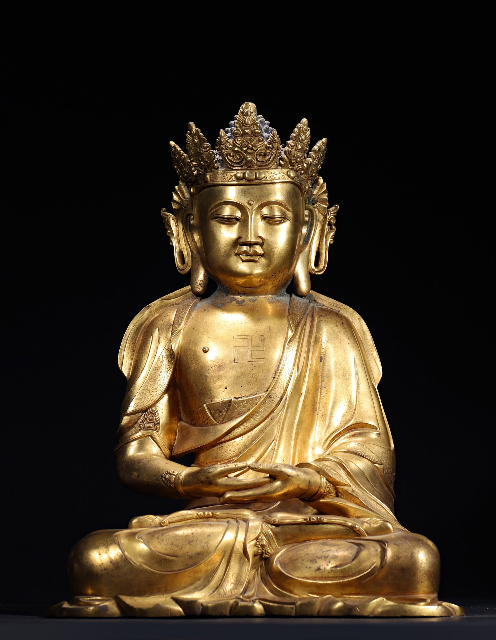 A GILT-BRONZE CROWNED VAIROCANA BUDDHA: A gilt-bronze crowned Vairocana Buddha seated in dhyanasana, wearing engraved robes. Dimensions: 32 x 22 x 45 cm; Wt. 12,500 g.