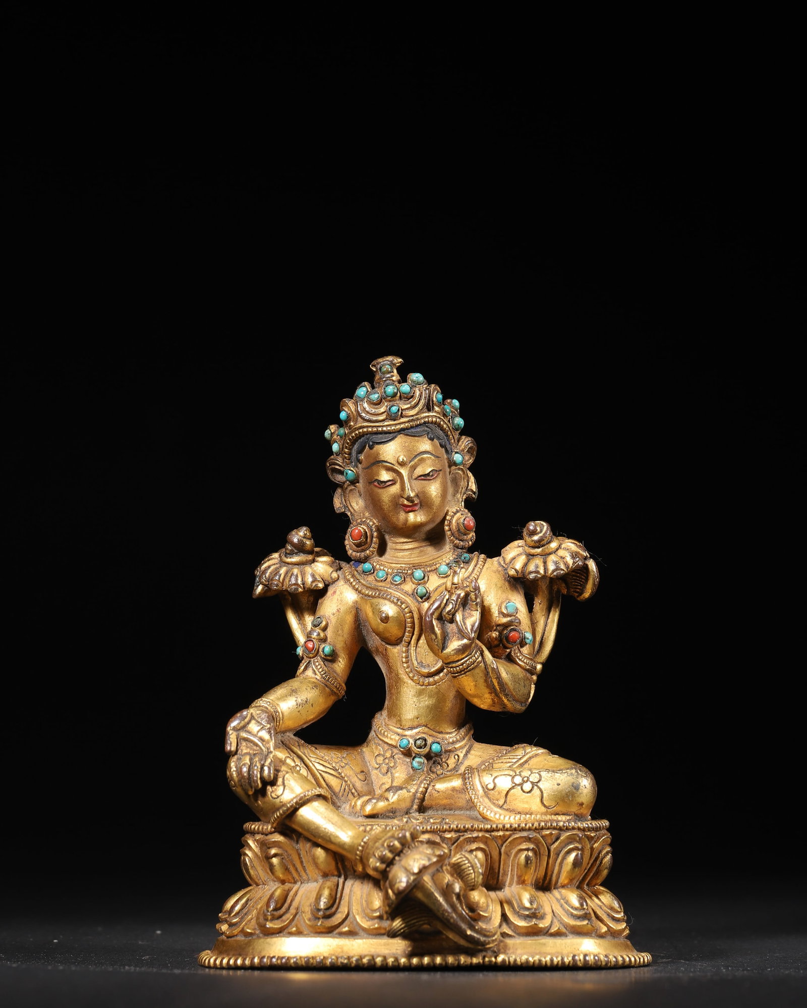 A GILT-BRONZE FIGURE OF GREEN TARA WITH COLORED-STONE INLAY: A gilt-bronze figure of Green Tara seated in lalitasana on a lotus base, set with colored stones. The base bears a vajra motif. Dimensions: 9 x 8 x 12 cm; Wt. 522 g.