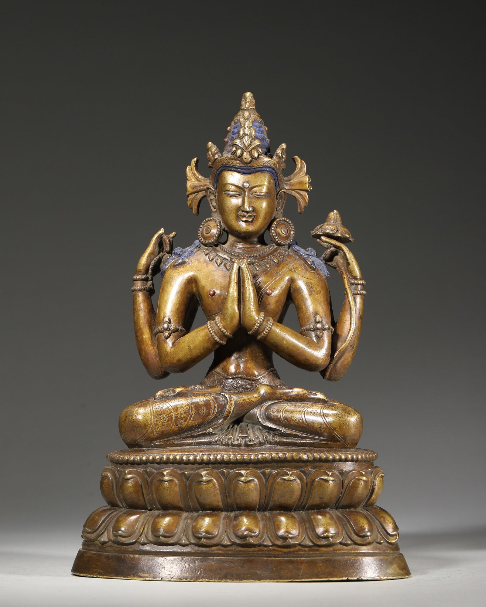A COPPER FIGURE OF FOUR-ARMED AVALOKITESHVARA: A copper figure of Four-Armed Avalokiteshvara seated on a double-lotus base, with ritual hand gestures and a sealed base. Dimensions: 15 x 10 x 22 cm; Wt. 1,970 g.