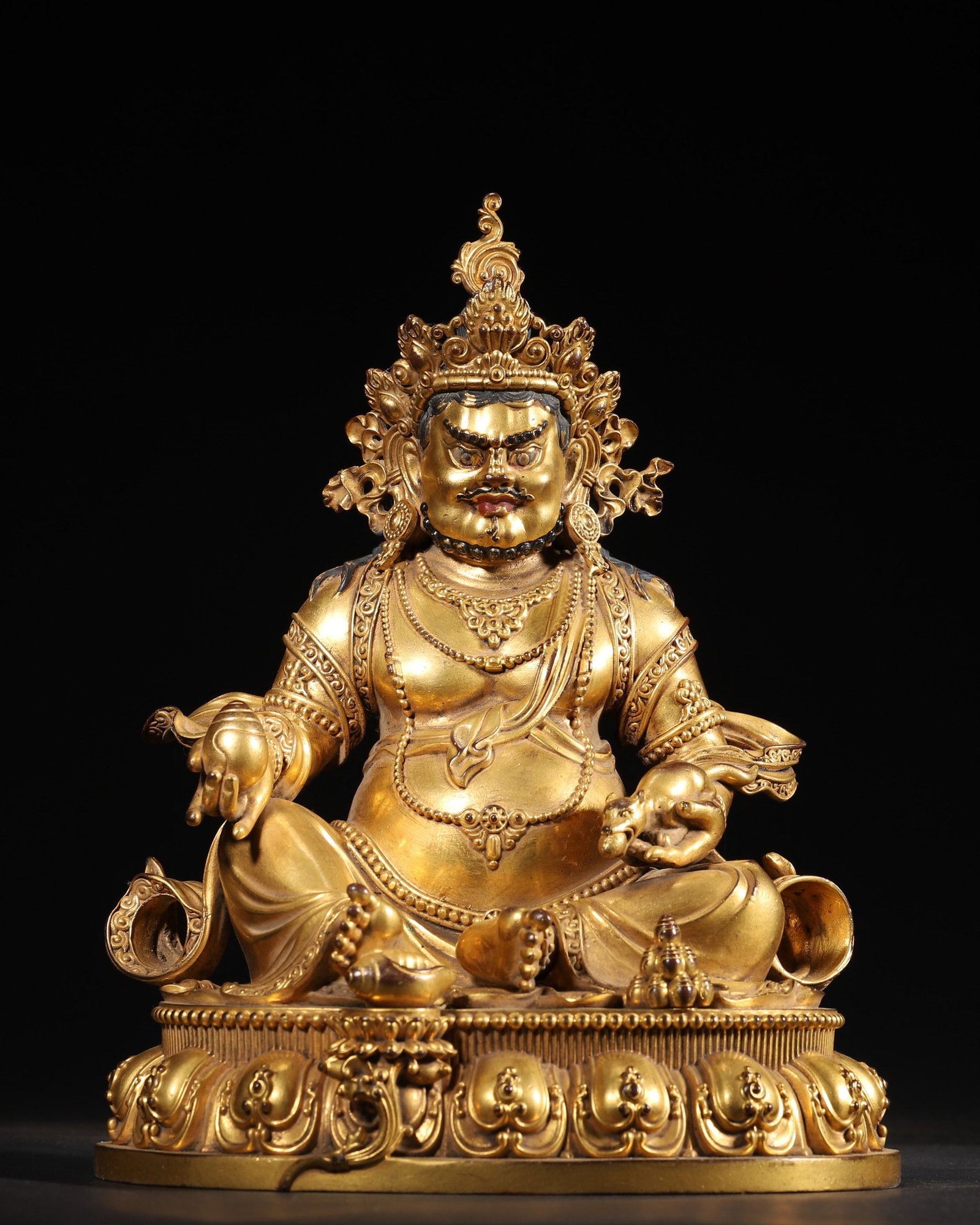 A GILT-BRONZE FIGURE OF YELLOW JAMBHALA: A gilt-bronze figure of Yellow Jambhala seated on a lotus base, with a crossed-vajra motif to the base. Dimensions: 18 x 15 x 23 cm; Wt. 3,436 g.