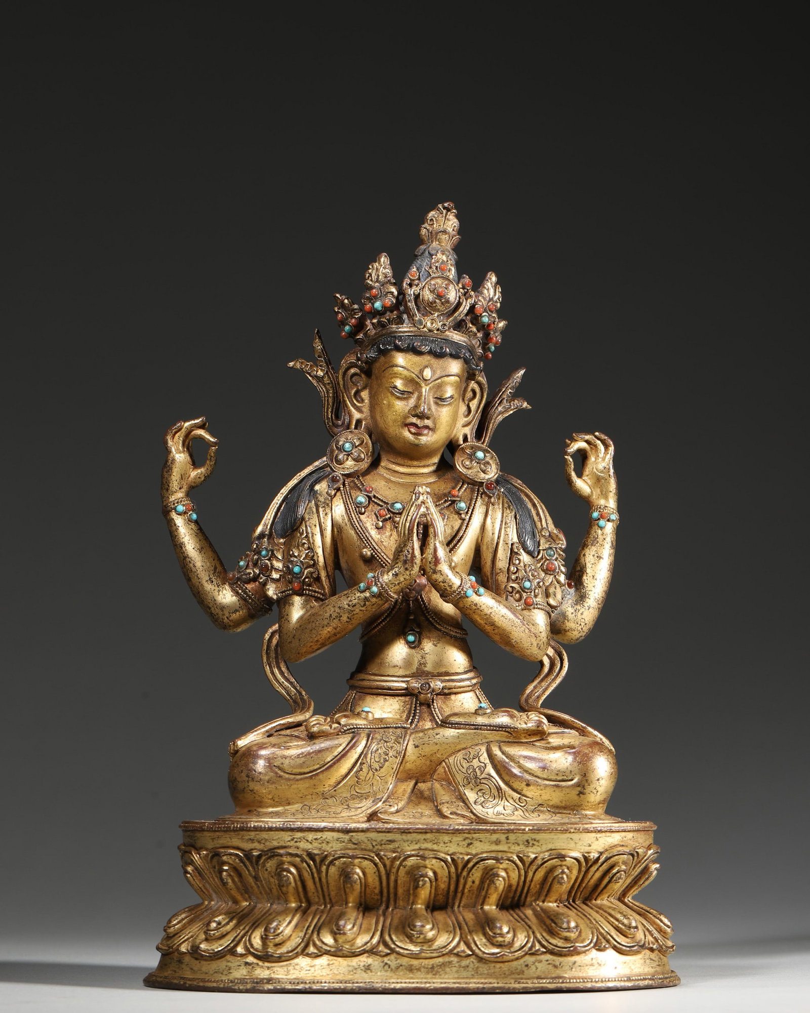 A GILT-COPPER-ALLOY FIGURE OF FOUR-ARMED AVALOKITESHVARA WITH COLORED-STONE INLAY: A gilt-copper-alloy figure of Four-Armed Avalokiteshvara seated on a double-lotus base, set with colored stones and with a vajra motif to the base. Dimensions: 14 x 11 x 21 cm; Wt. 1,534 g.