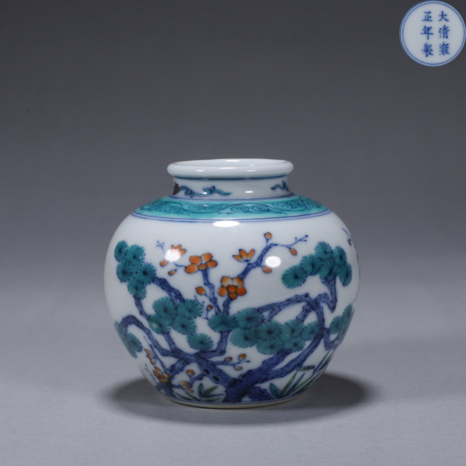 A DOUCAI 'PINE, BAMBOO AND PLUM' PORCELAIN JAR: A small doucai porcelain jar painted with pine, bamboo and plum motifs. The base bears a mark described in the source as Yongzheng. Diam. 9.8 cm; Ht. 9.5 cm.