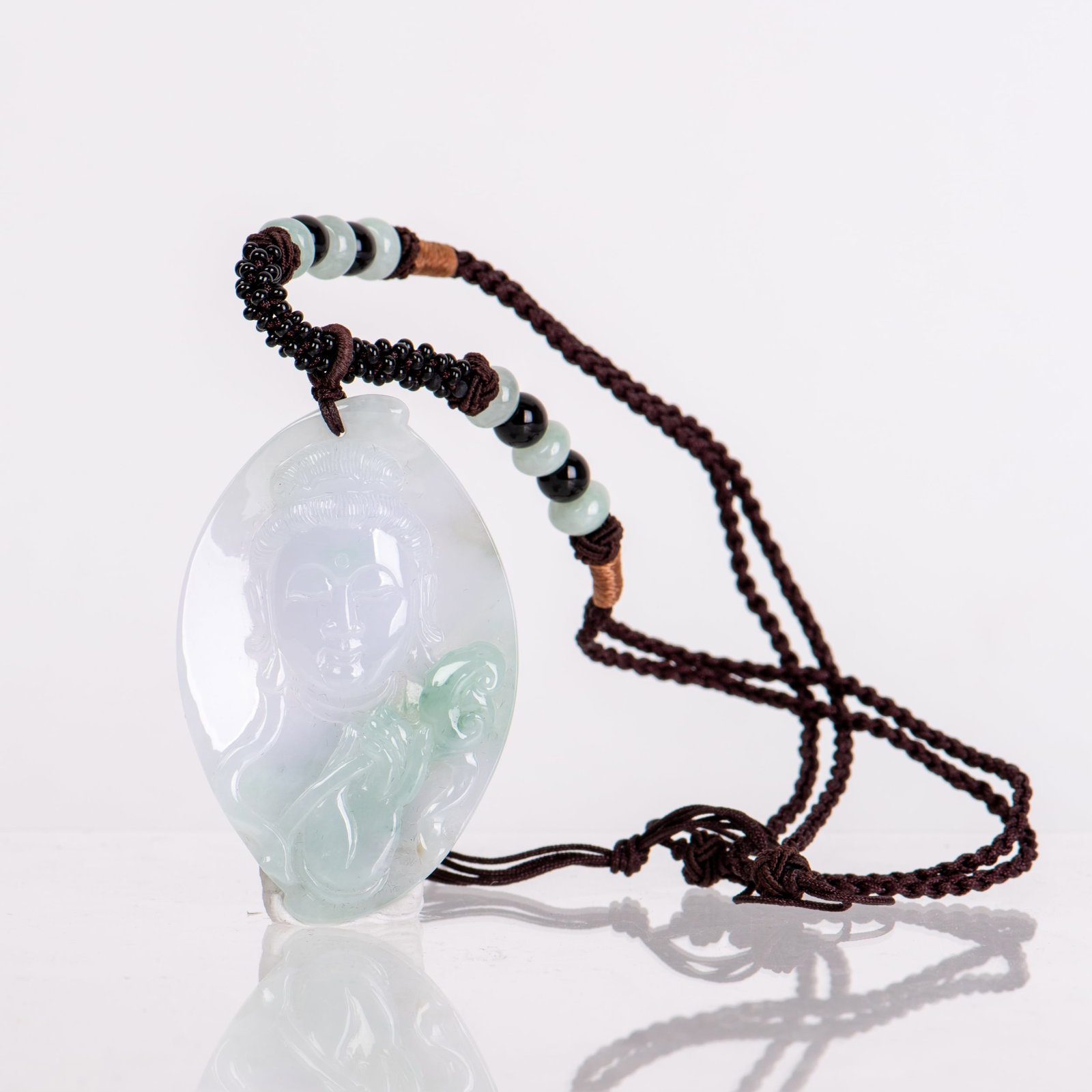 A JADEITE GUANYIN PENDANT: A jadeite Guanyin pendant. 2.25"h x 0.25"w x 1.5"l (5.72 x 0.64 x 3.81 cm)