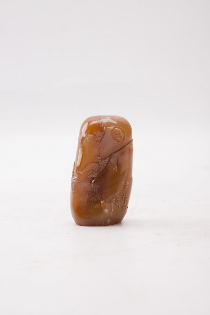 A Carved Chinese Soapstone Seal: Carved soapstone seal stamp, of rectangular form with rounded edges, with the design of landscape scenery and Chinese inscription, of caramel coloration. Height 2.75"