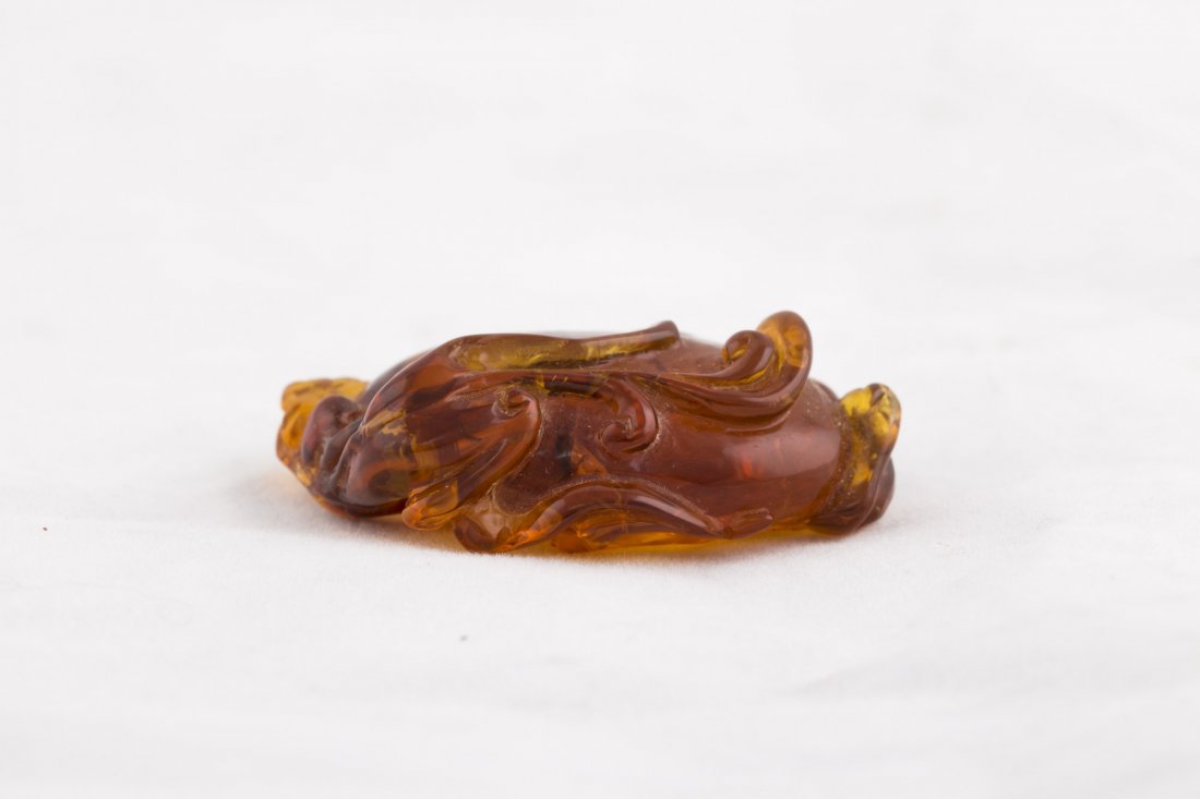 Amber Pendant: A superby crafted translucent brown Amber Pendant features a single peach associated blessings of longevity. 20th century. Propery from a Miami collector. Length 1.75" Width 0.5" Height 1.25"