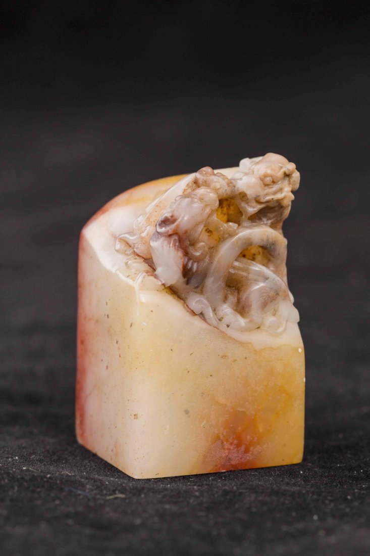 Chinese Soapstone Seal: Chinese soapstone seal surmounted by mythological creatures, of rectangular form, of yellowish and red-brown coloration. Length 1" Width 1" Height 2"