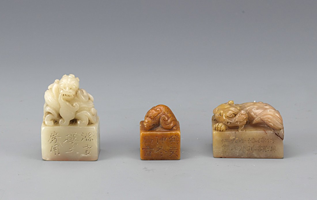 A Group of Three Soapstone Seal: A group of three Shou Shan Soapstone Seals. Each soapstone seal is surmounted by a mysterious beast and its base inscribed with Chinese calligraphy. Length 1.25'' Width 0.75'' Height 2'' (Largest Seal