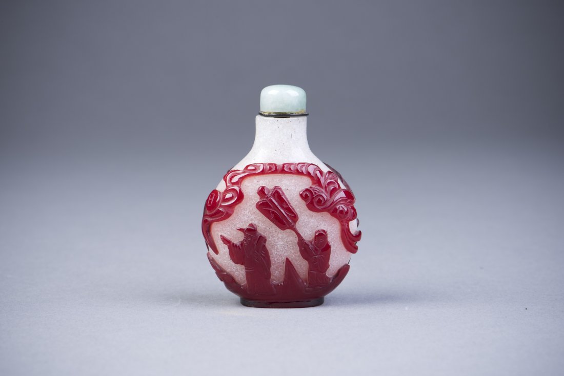 Peking Glass Snuff Bottle: A Peking Glass Snuff Bottle with red overlay Scene of ancient Chinese characters and a translucent stone cap. Height 3'' Width 2'' Length 1''
